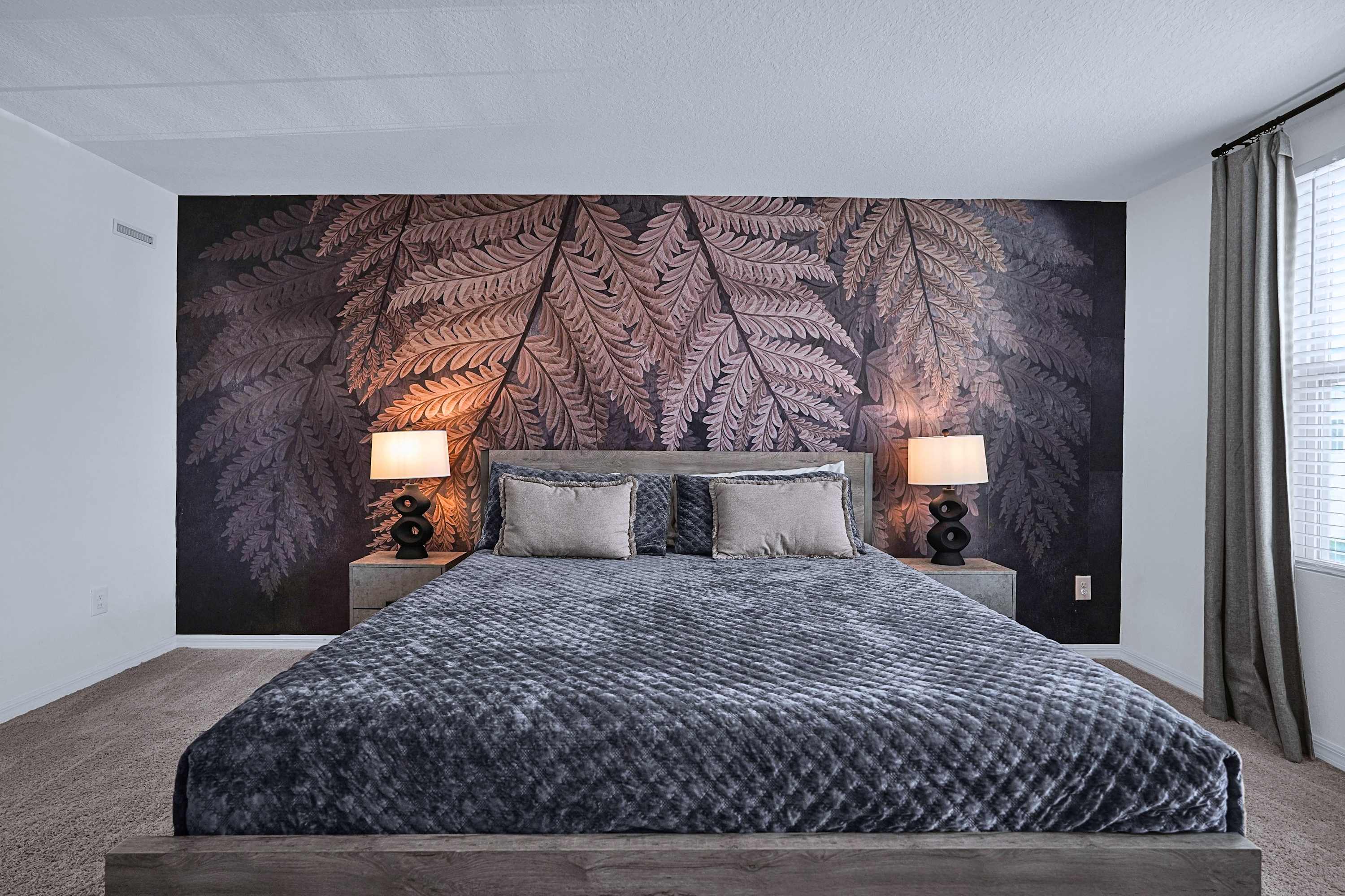 Elegant king bedroom featuring modern wall details, bedside lighting, and cozy decor