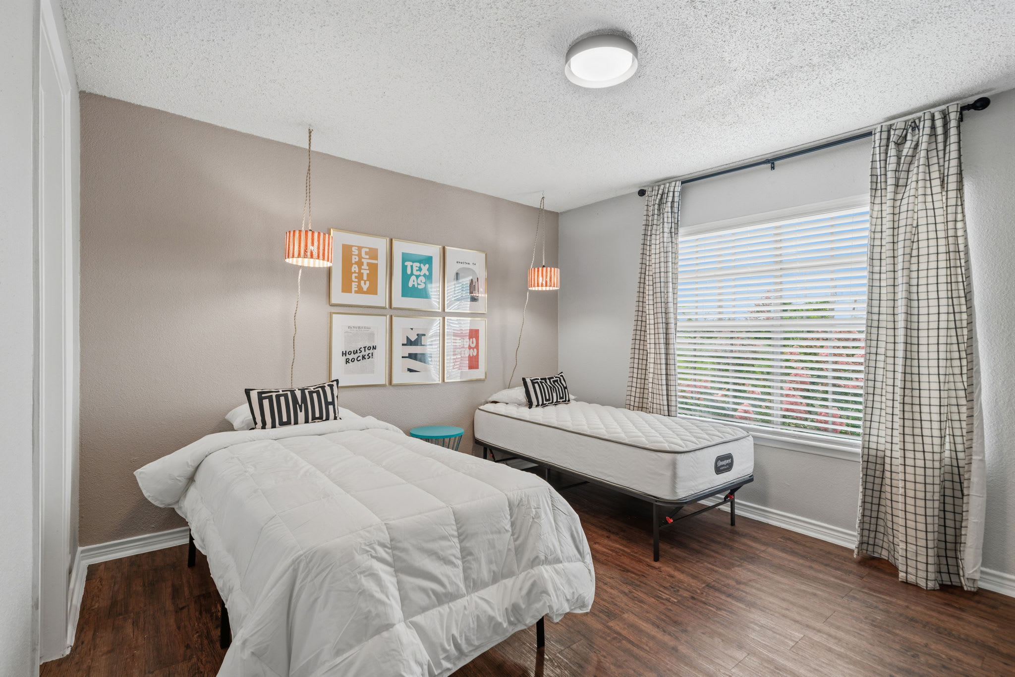 Cozy bedroom with twin beds, stylish decor, and ample natural light perfect for a restful stay.