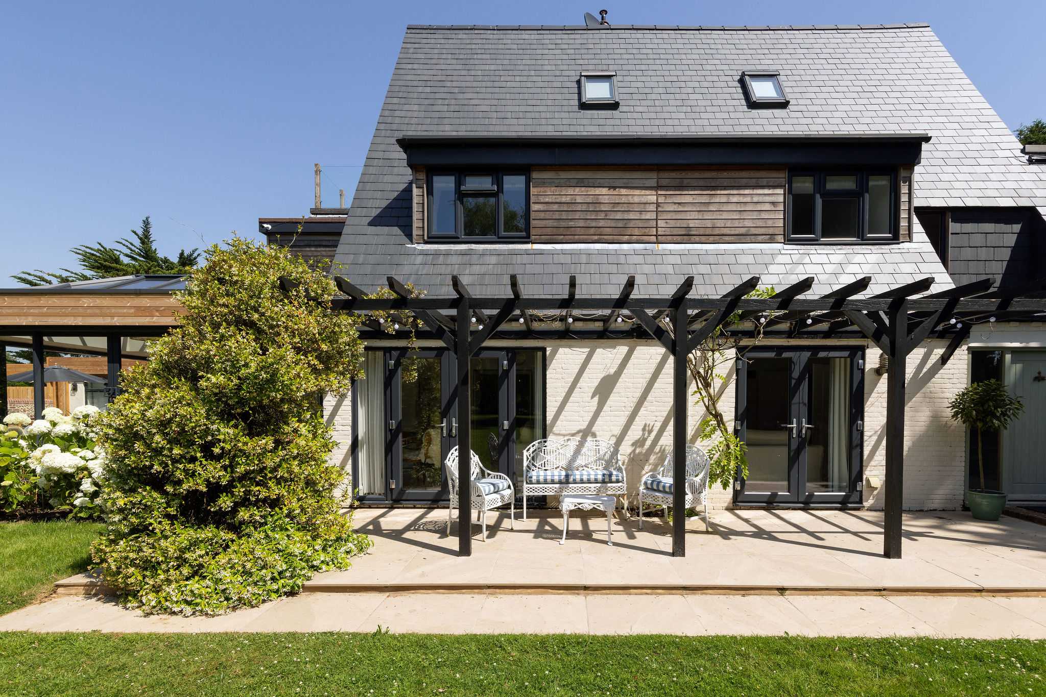 Contemporary holiday home exterior with covered terrace and inviting garden seating area