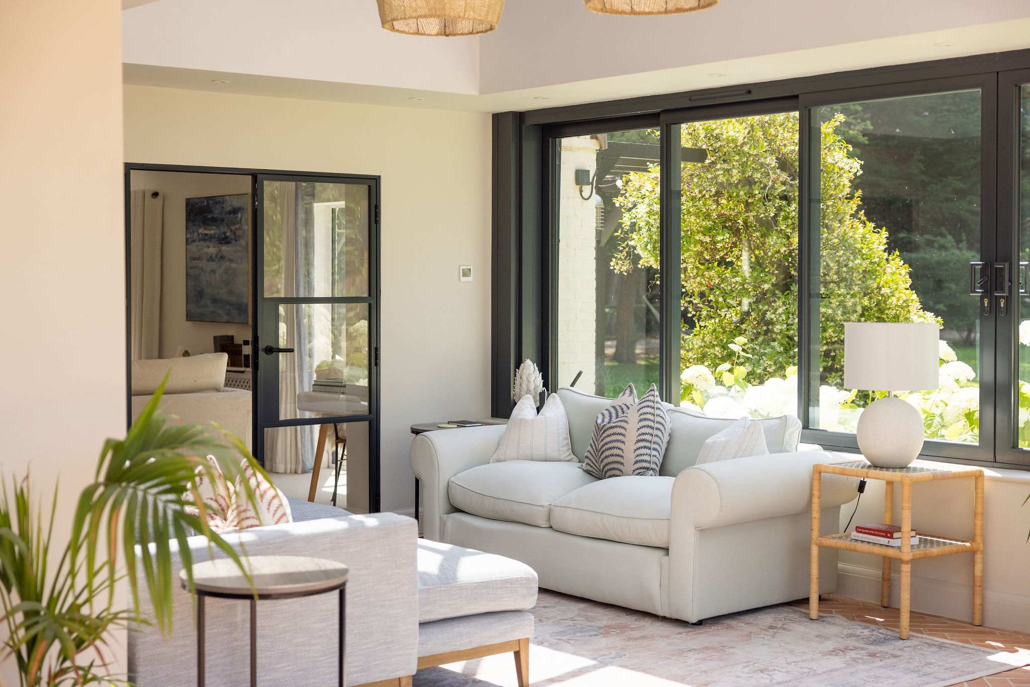 Inviting lounge corner with cosy armchairs and peaceful garden views through expansive windows