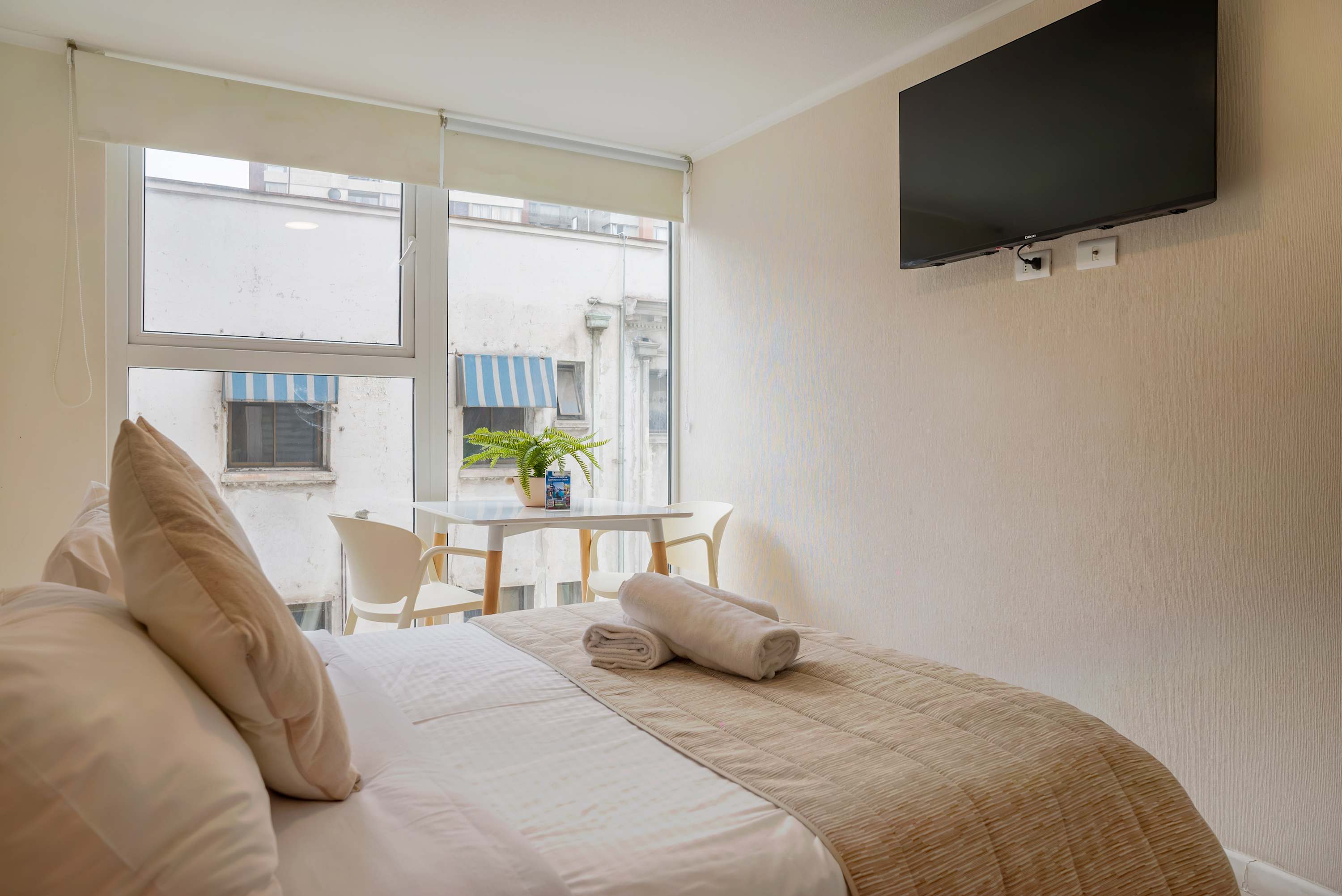 Cozy studio with natural light, comfy bed, and dining area for a relaxing stay.