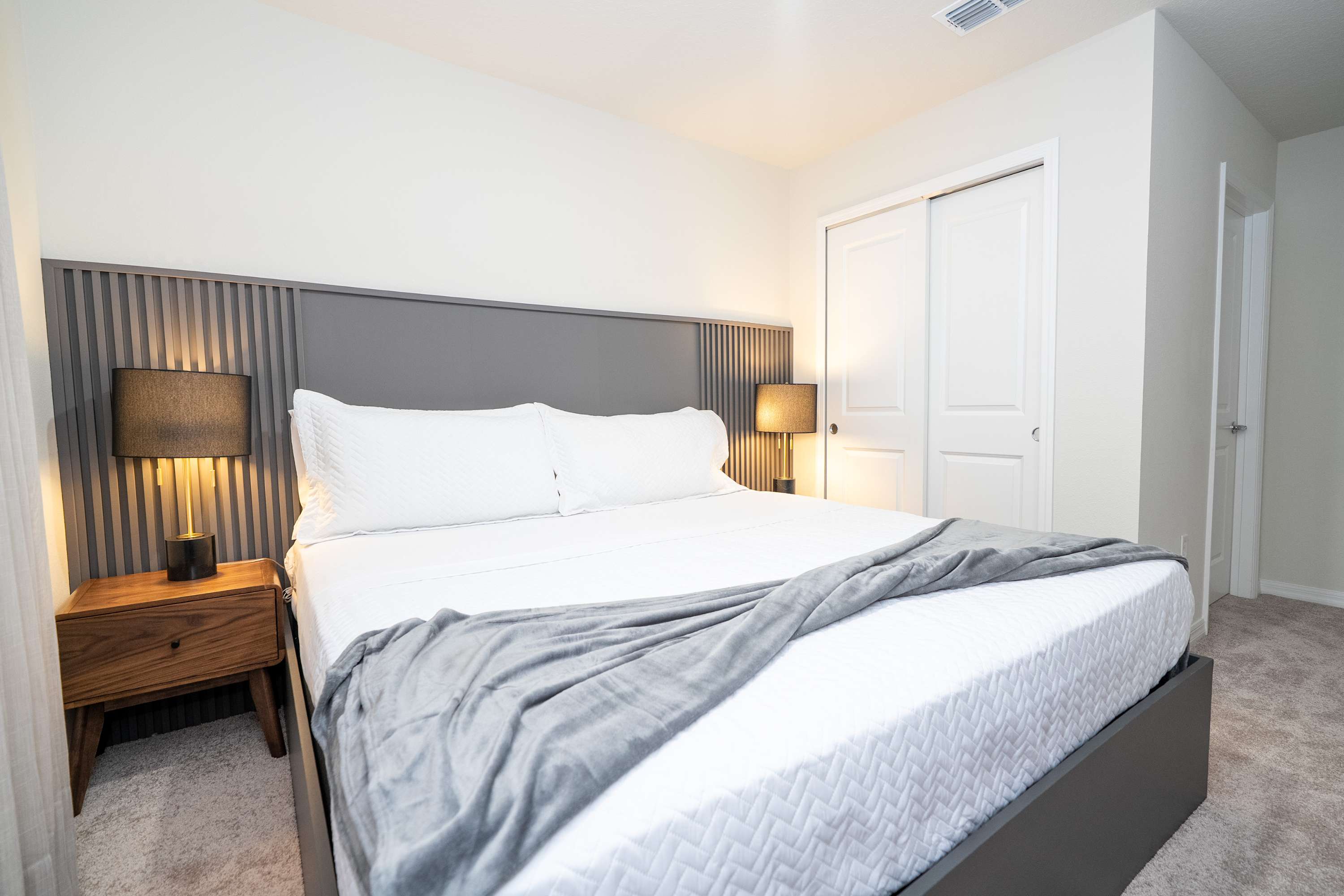 A plush king bed featuring a classic statement headboard and warm, inviting bedside lamps