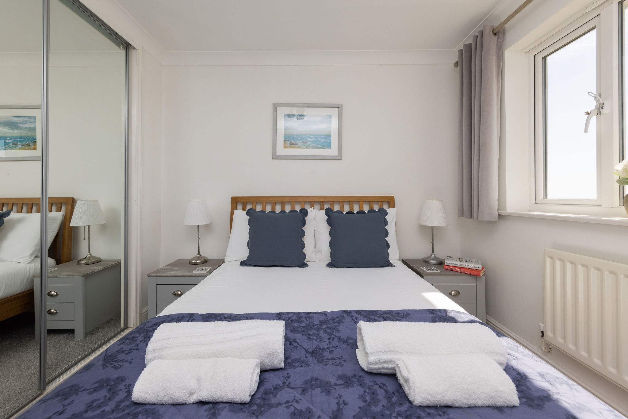 Comfortable and stylish bedroom with mirrored wardrobes, perfect for a restful seaside getaway.