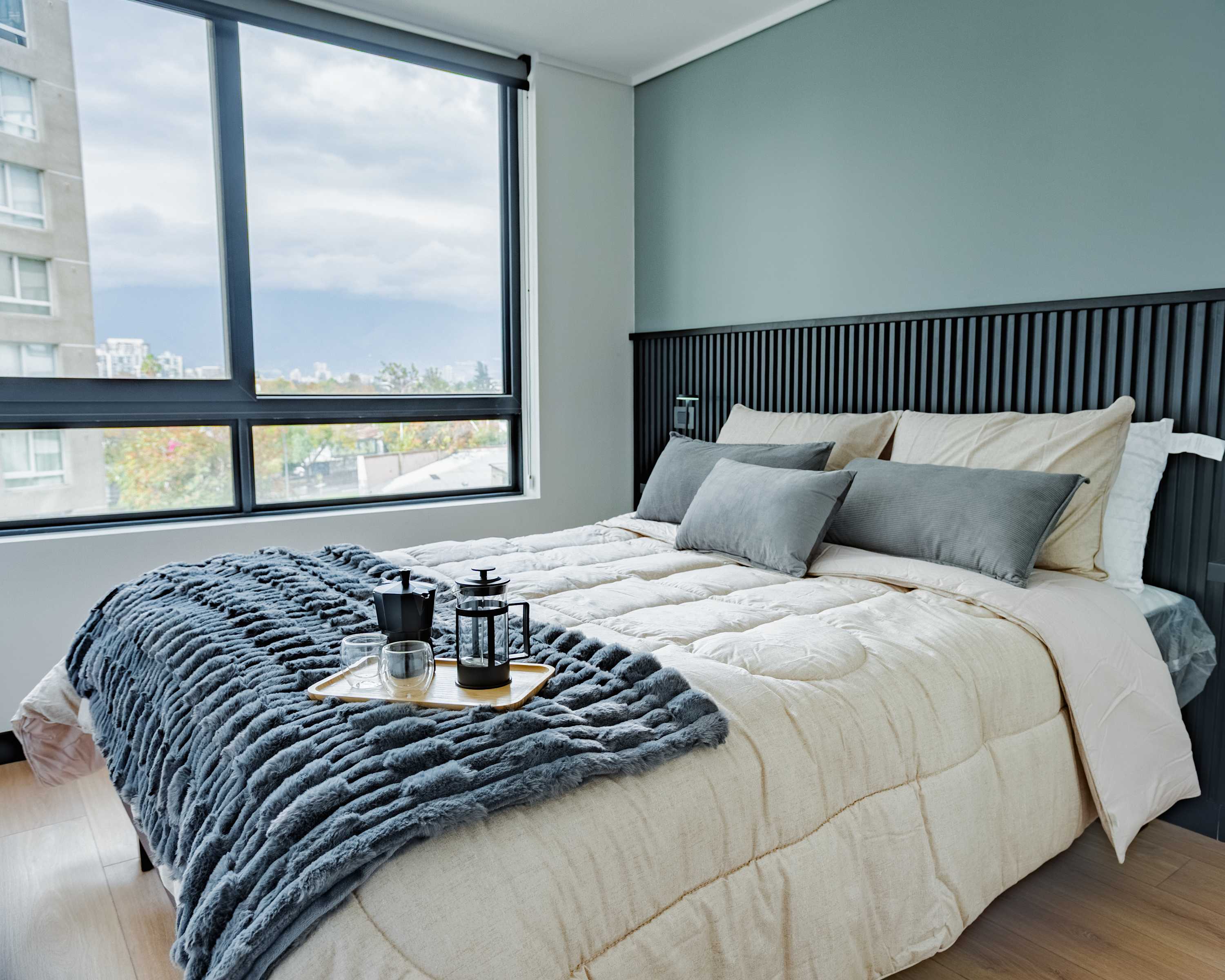 Relax in this serene bedroom with city views, featuring plush bedding and a cozy ambiance perfect for unwinding.