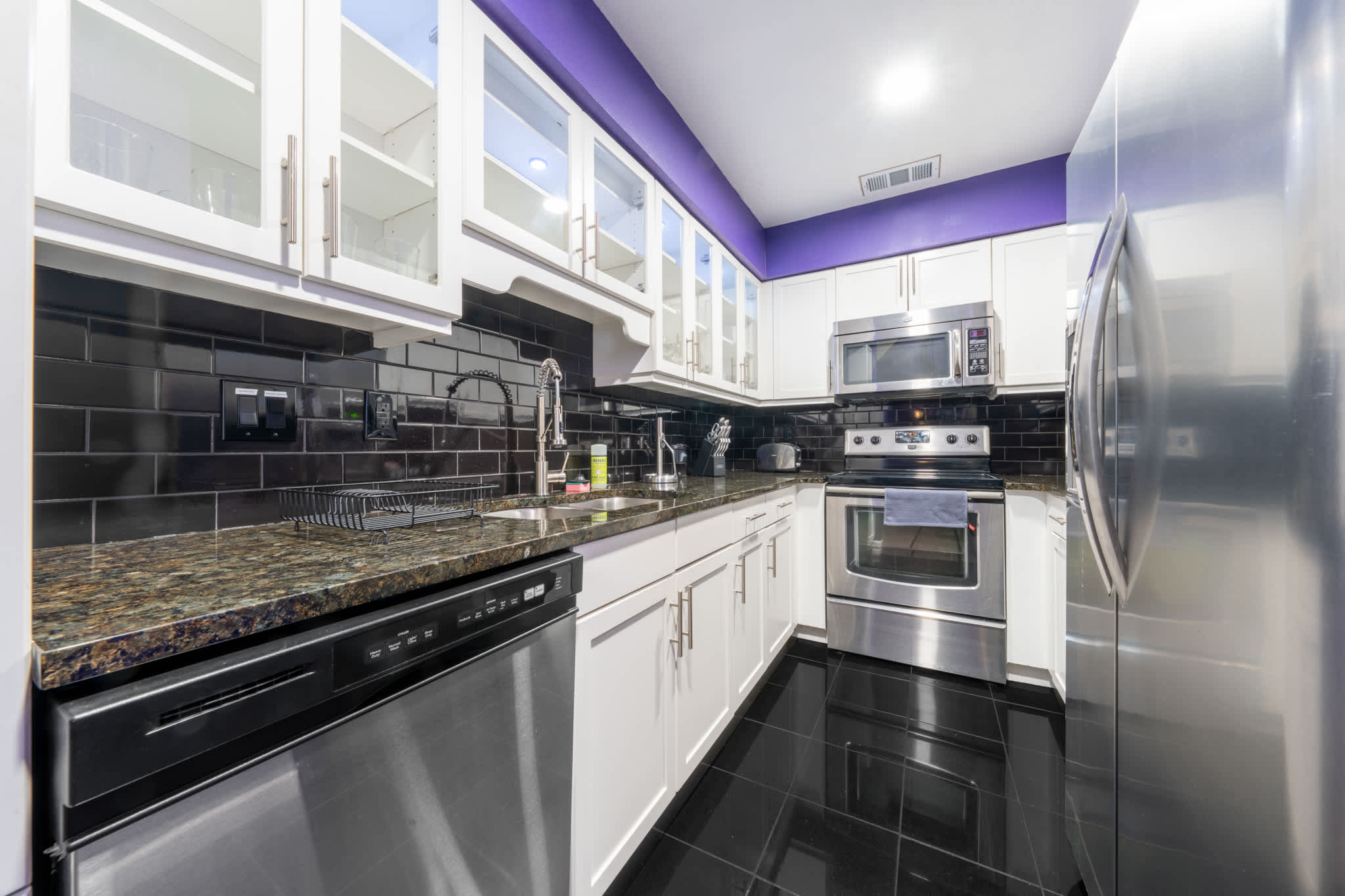 Sleek modern kitchen with stainless steel appliances and stylish black backsplash, perfect for culinary adventures.