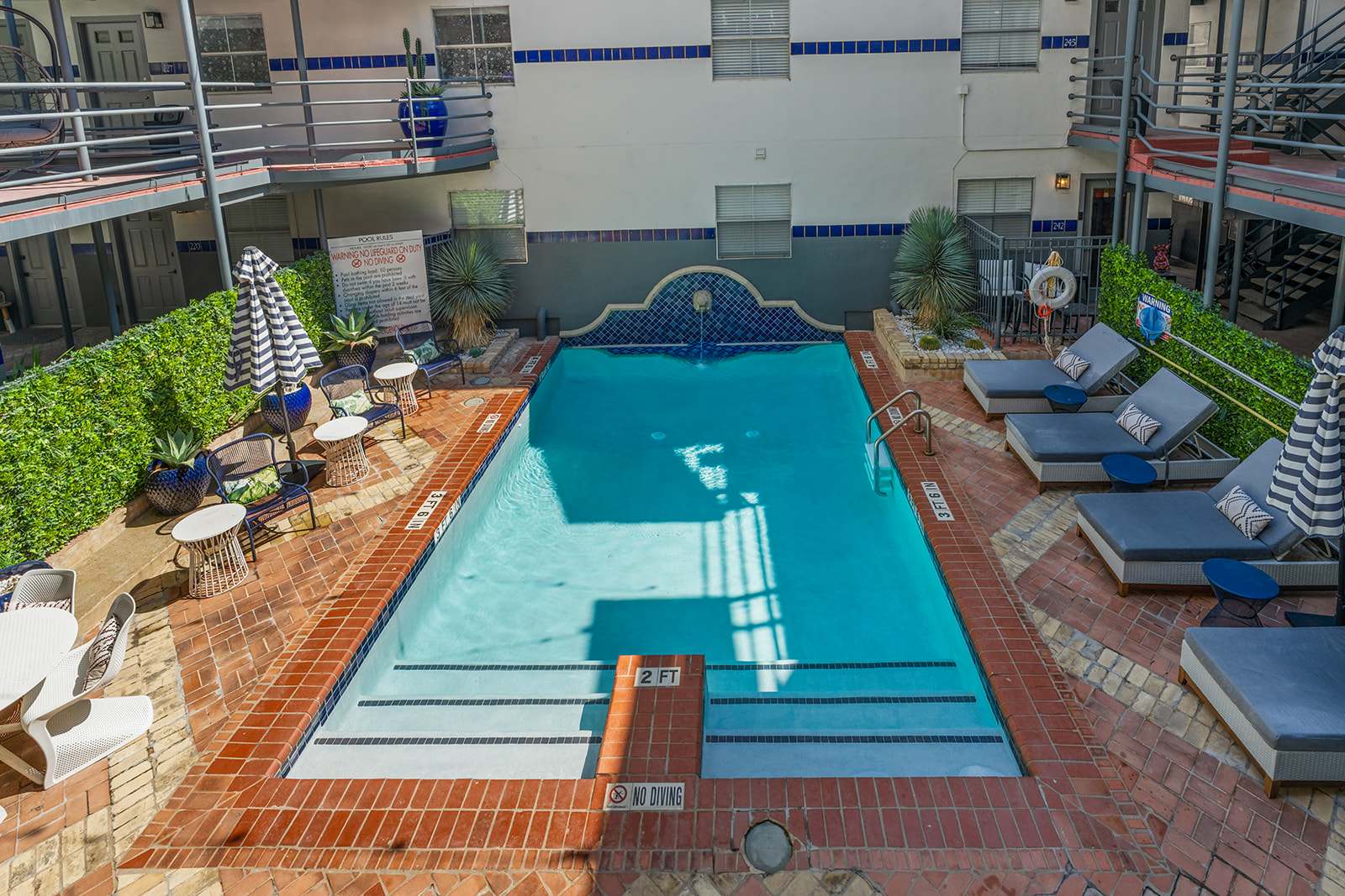 Relax by the inviting poolside with comfortable loungers and lush greenery, perfect for a sunny day retreat.