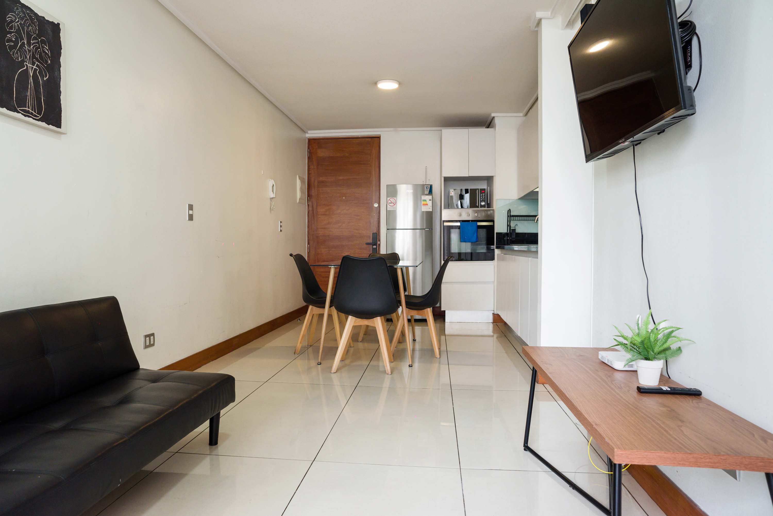 Private living and dining area with a glass table, four chairs, leather sofa, and fully equipped modern kitchen.