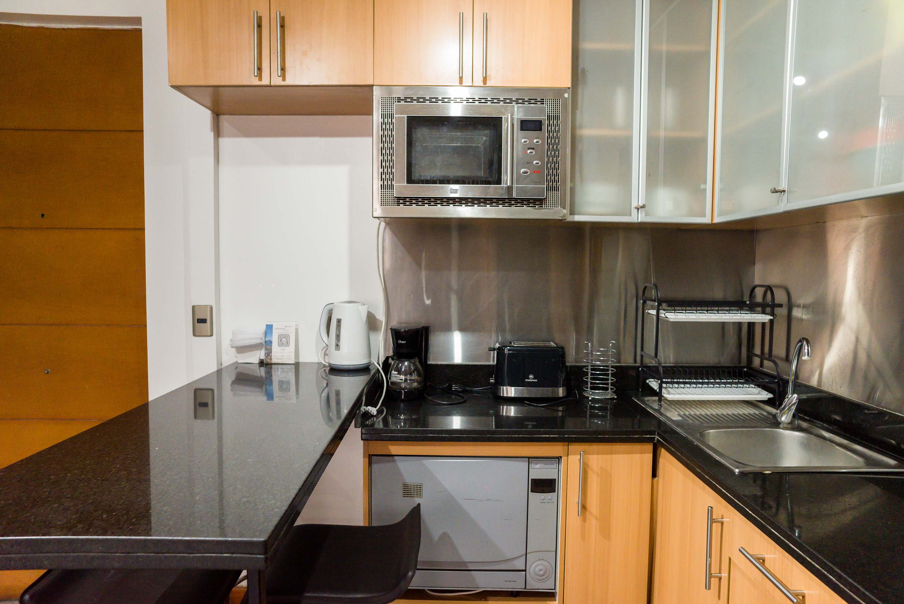 Modern kitchen with essential appliances and a sleek countertop, perfect for quick meals and coffee breaks.