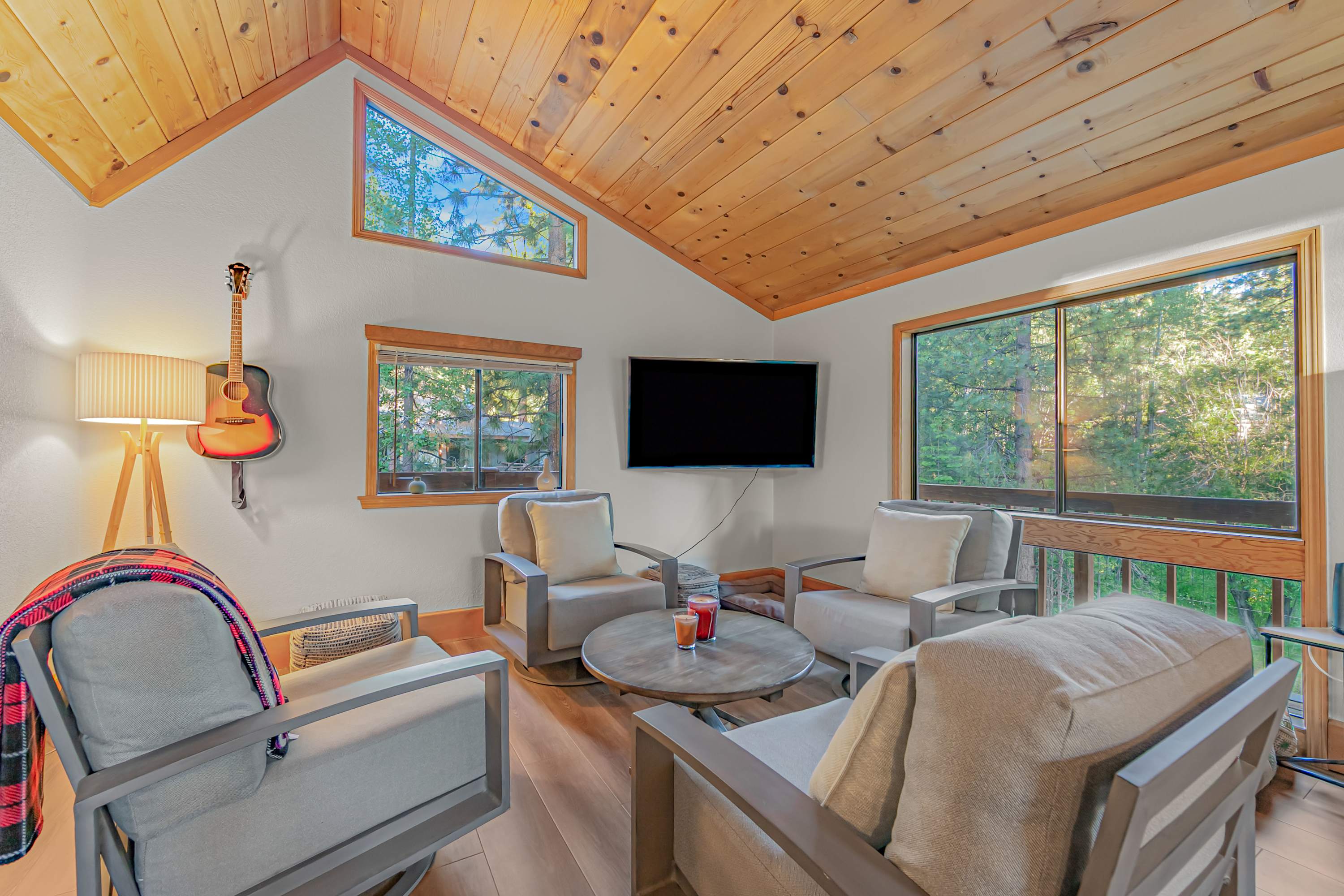 Unwind in the bright, inviting living room featuring comfortable seating, large windows, and views of the surrounding forest