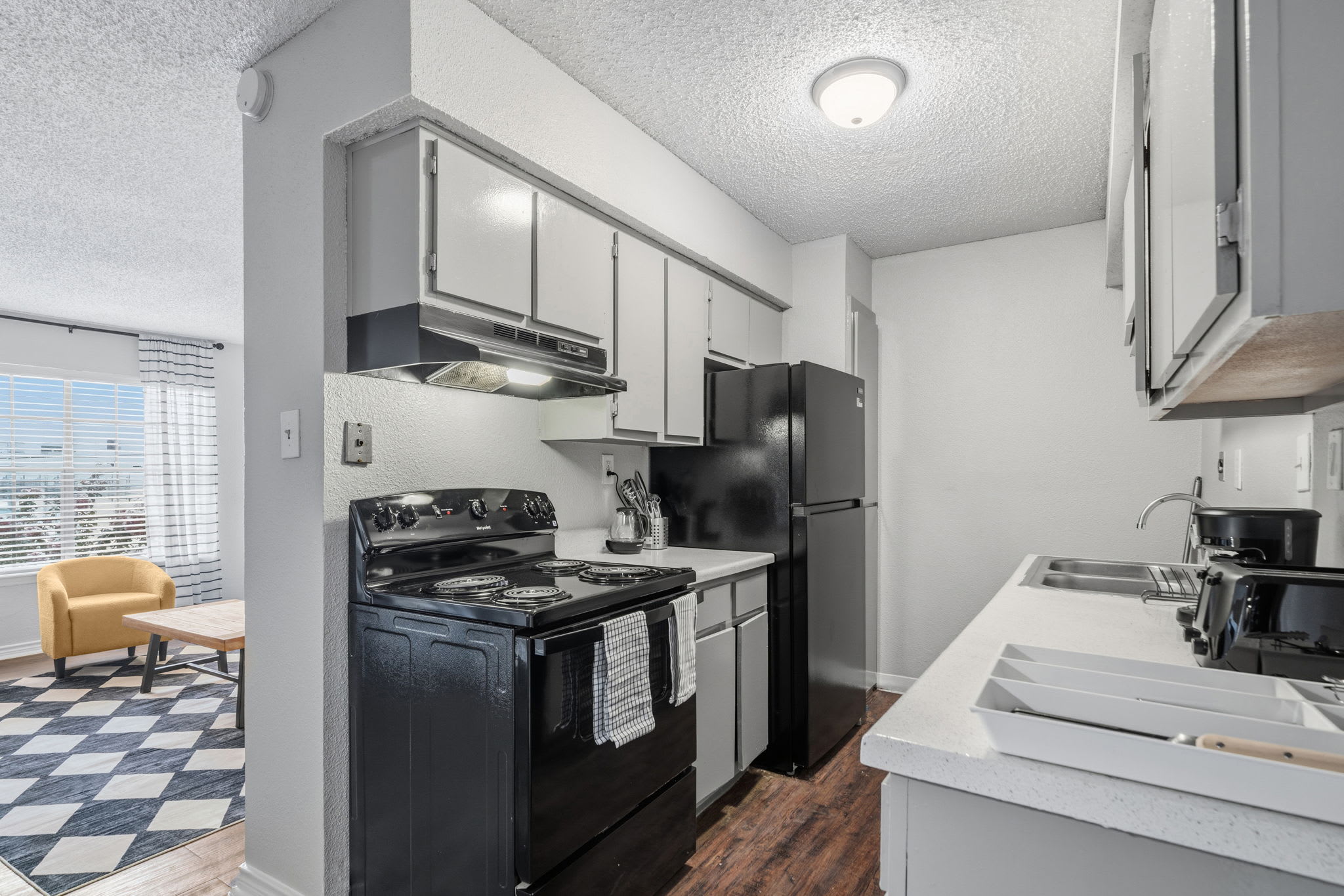 Modern kitchen with sleek black appliances and a cozy view into the living area, perfect for cooking and relaxation.