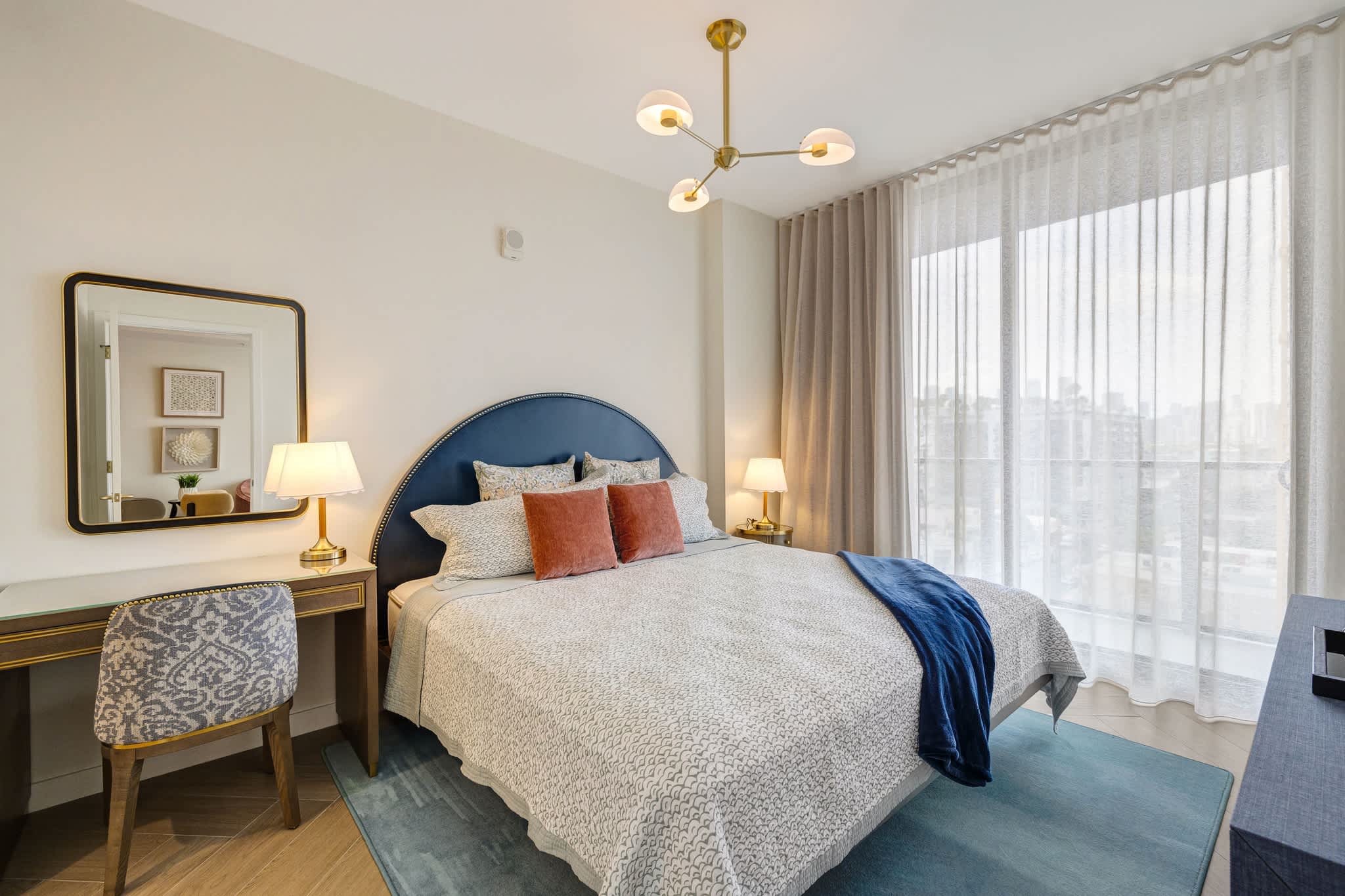 Relax in this stylish bedroom with a plush bed, chic decor, and ample natural light, perfect for a restful stay.