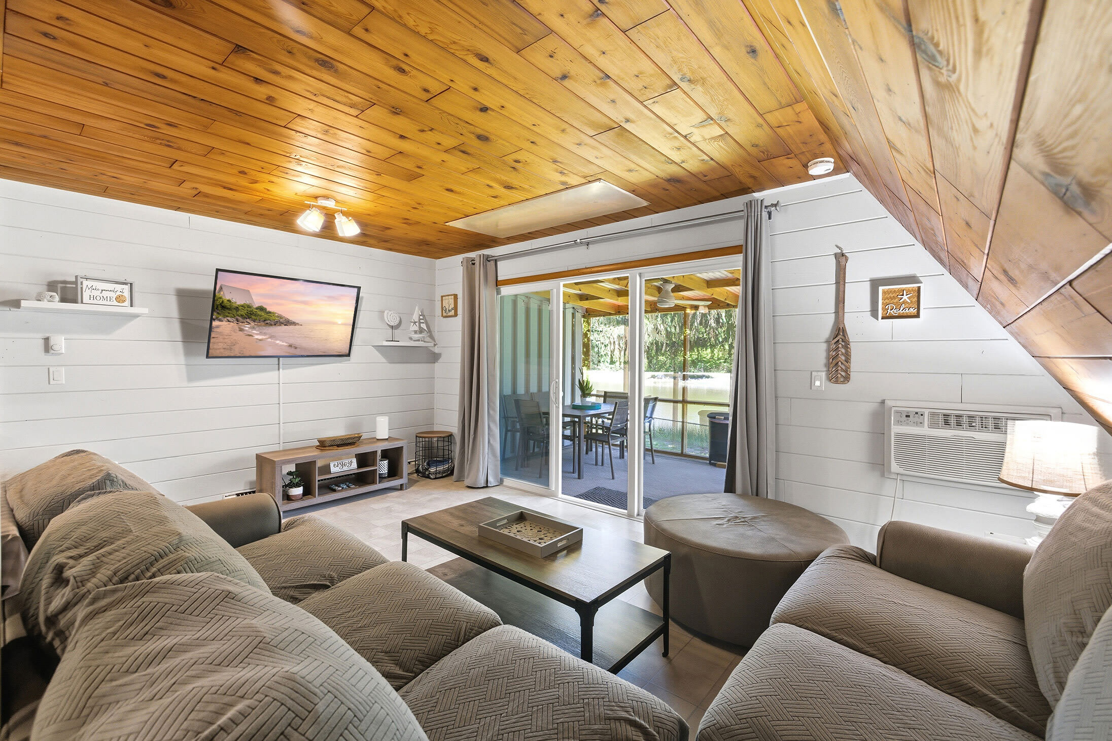 Living room includes a wall-mounted TV and direct deck access — easy to move between inside and out.