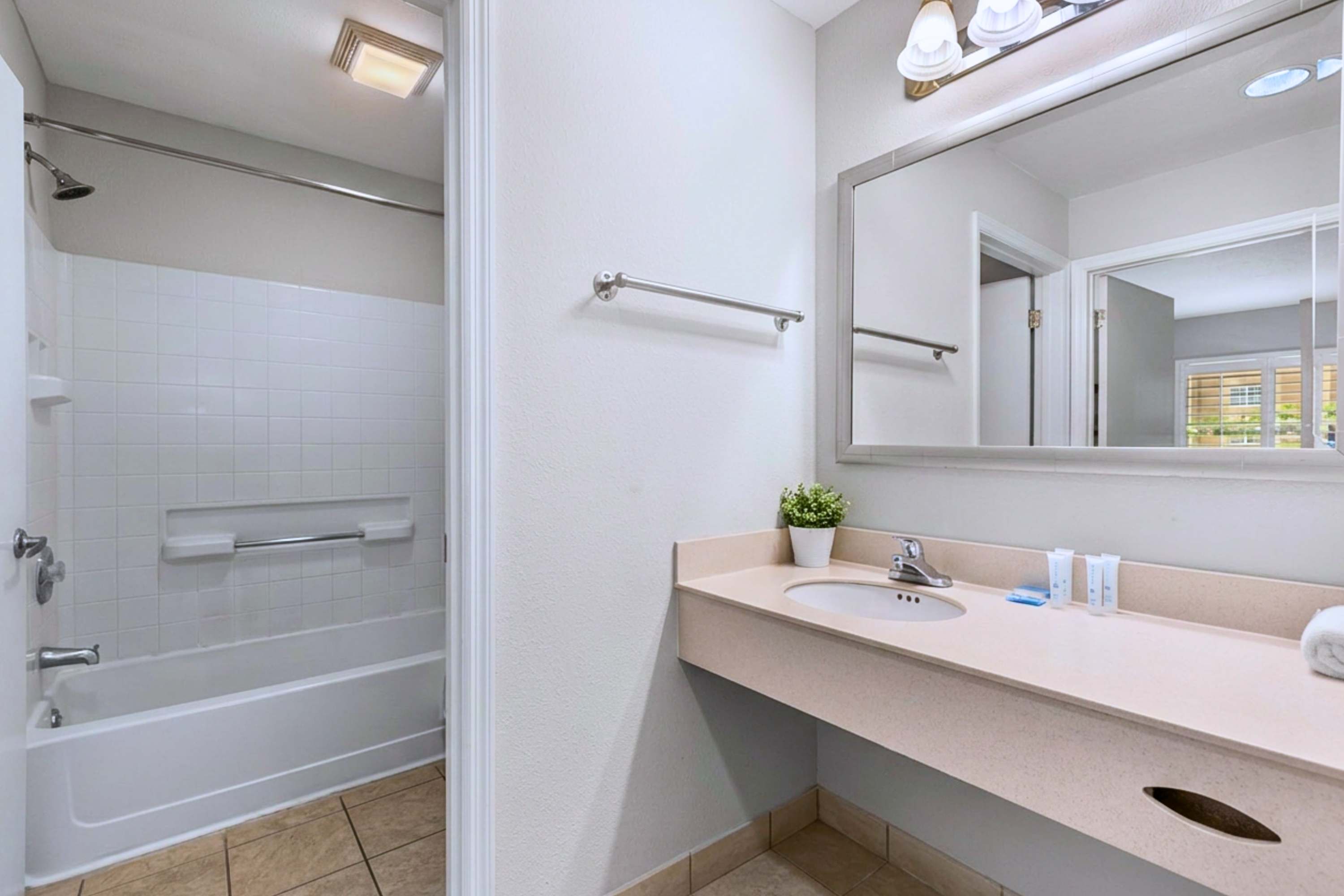 Soak or shower! Clean bath with large mirror and bathtub setup