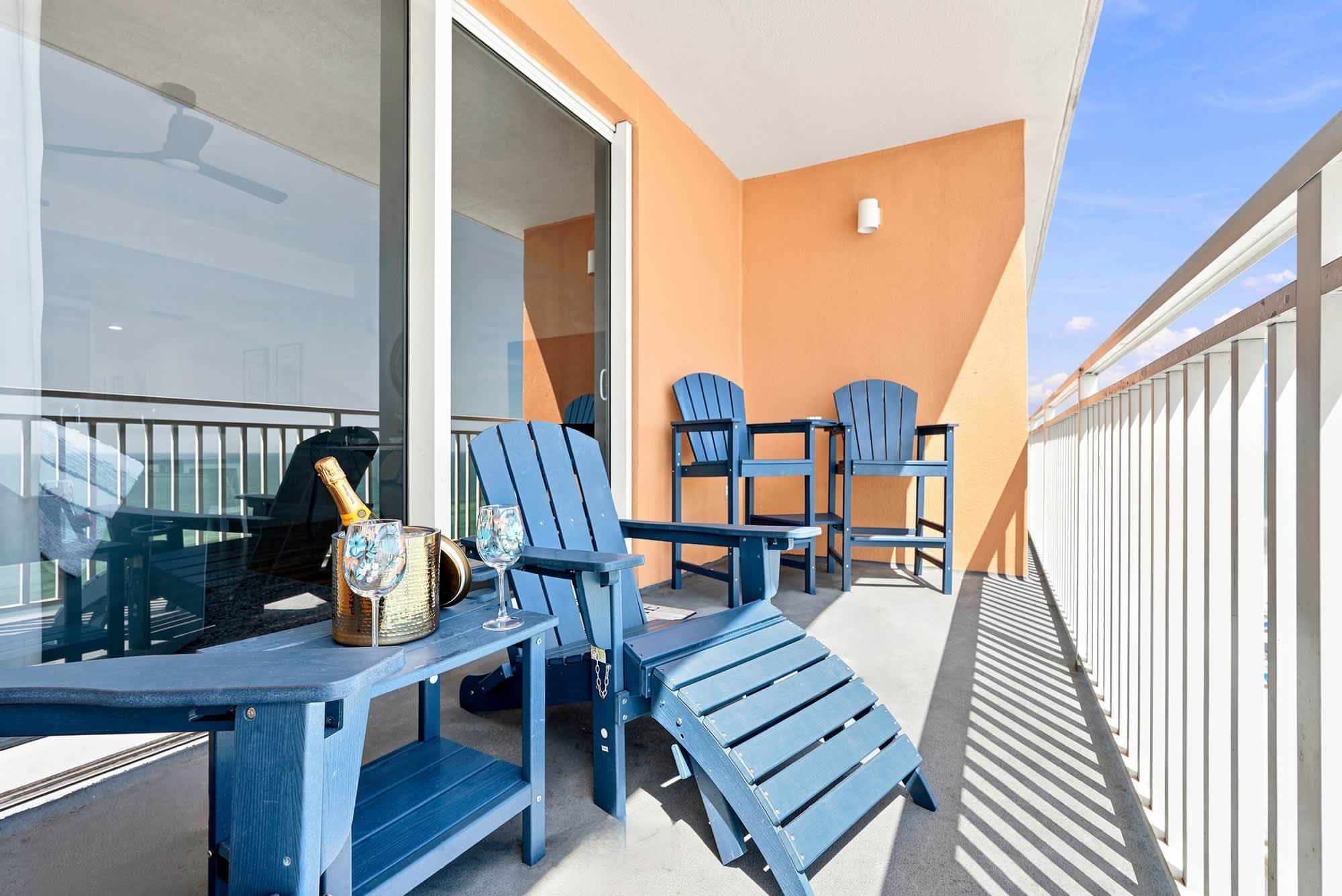 Splash 804E – Balcony with blue outdoor furniture, small table, and beach view.