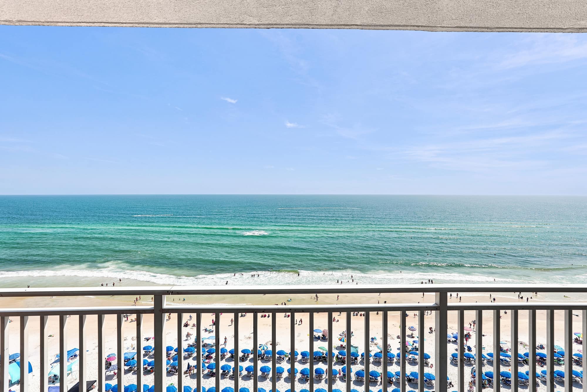 Splash 804E – Ocean view from a balcony overlooking a sandy beach with umbrellas and people.
