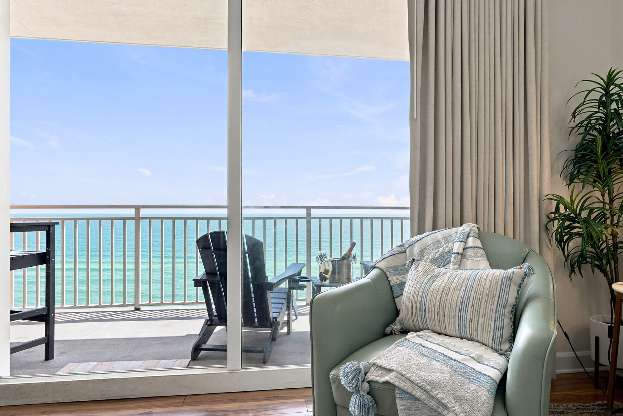 Splash 804E – Cozy living area with a green armchair and ocean-view balcony.