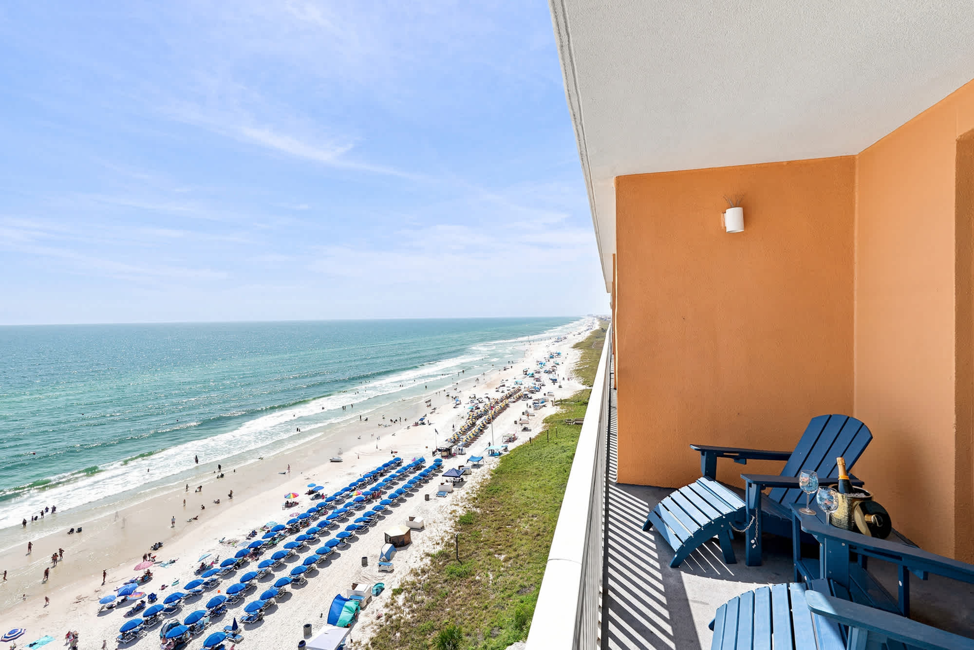 Splash 804E – Balcony view with blue chairs overlooking the beach, umbrellas, and ocean.