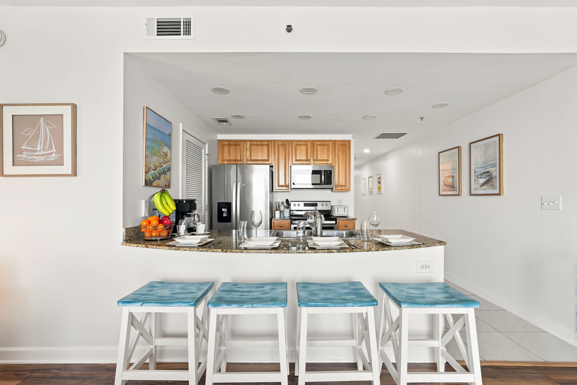 Splash 804E – Modern kitchen with granite countertops, stainless steel appliances, and four blue-topped bar stools.