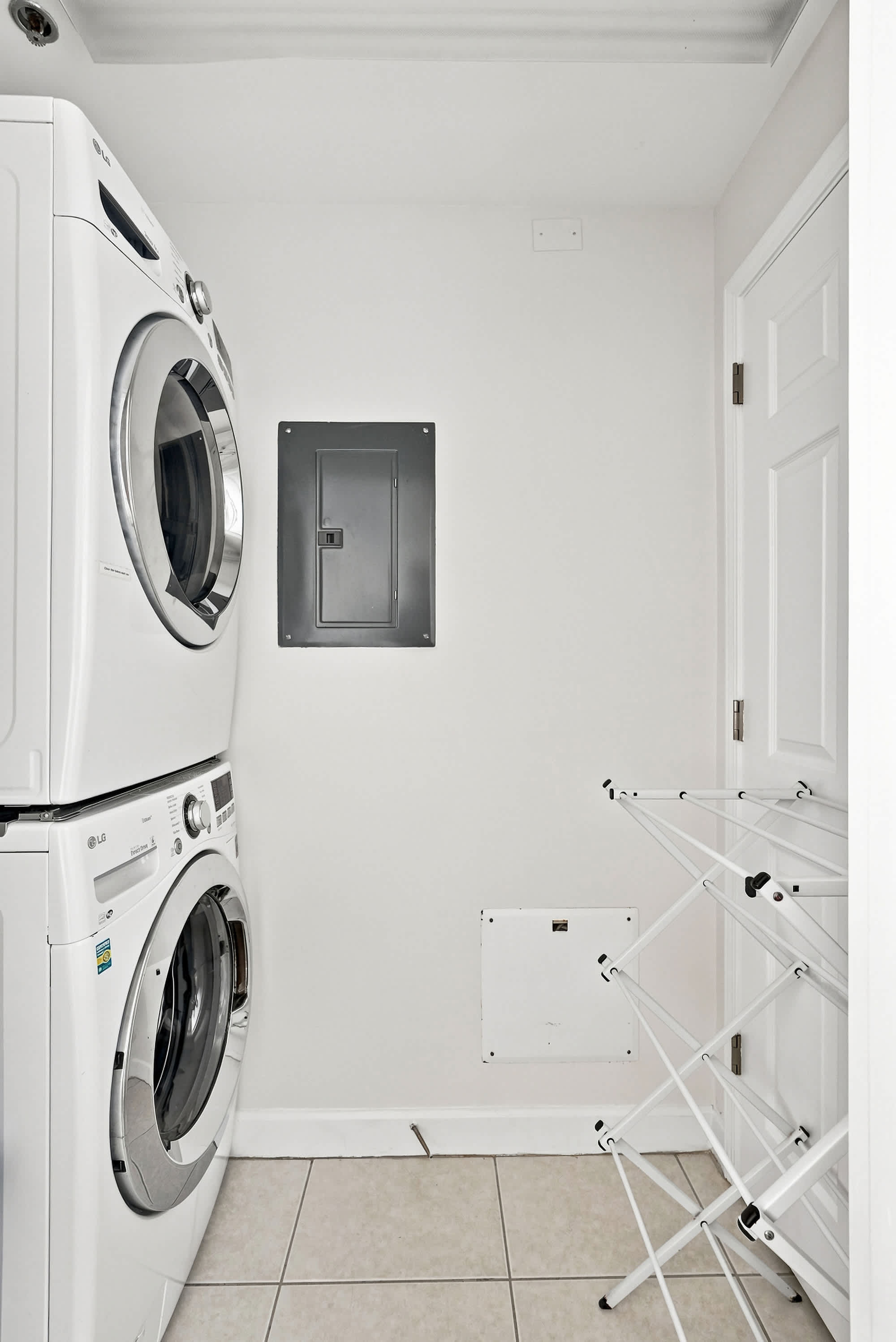 Splash 804E – Laundry room with stacked washer and dryer, electrical panel, and drying rack against a white wall.