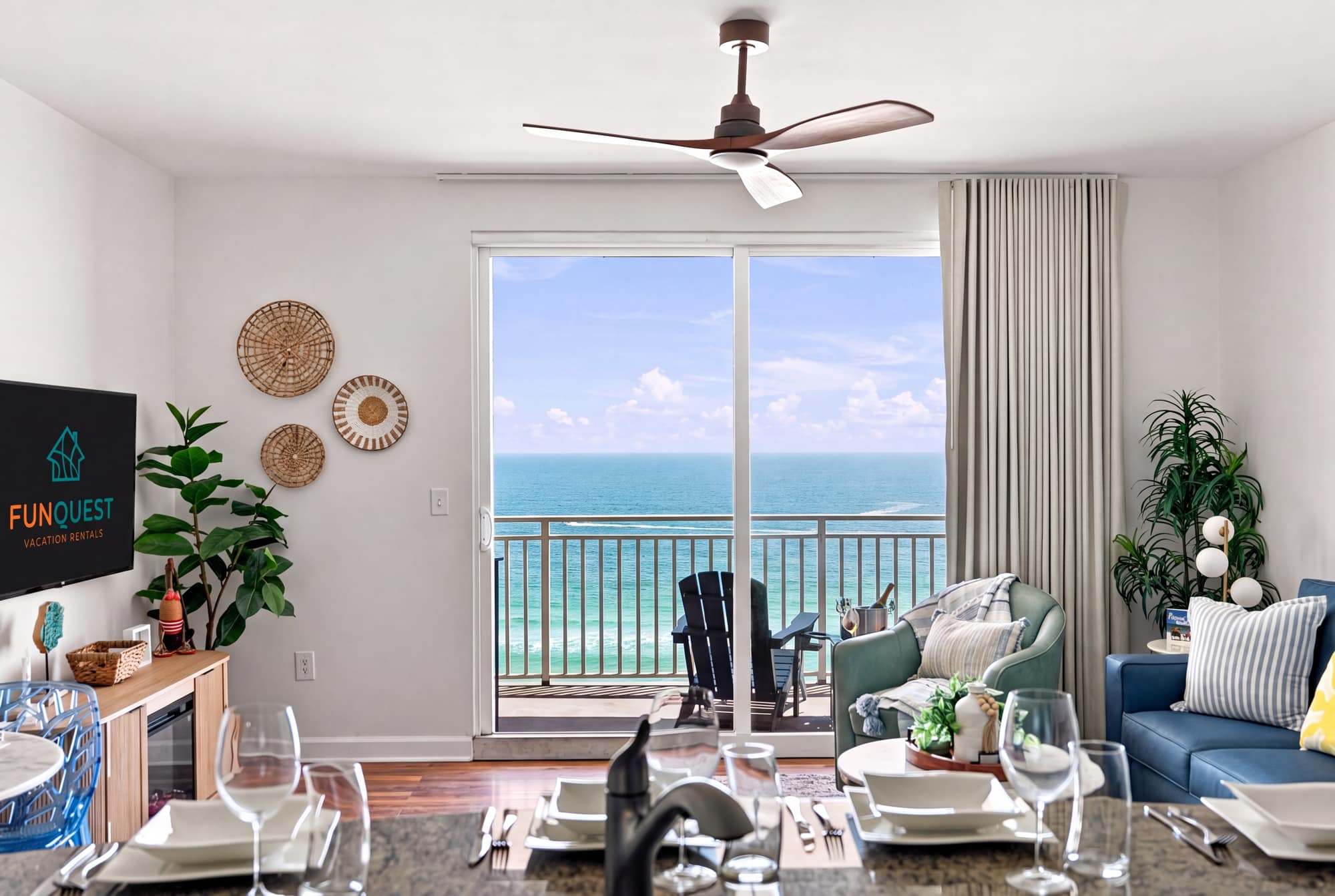 Splash 804E – Living room with ocean view, modern furnishings, plant, and dining setup featuring a table and dishes.