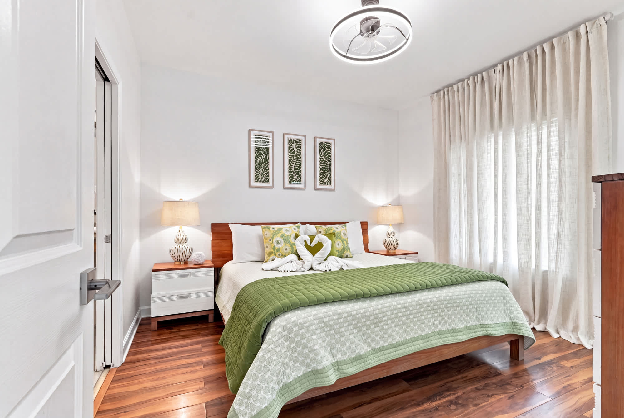 Splash 804E – Cozy bedroom with a queen bed, lamps, and green bedding, featuring wooden floors and large windows.