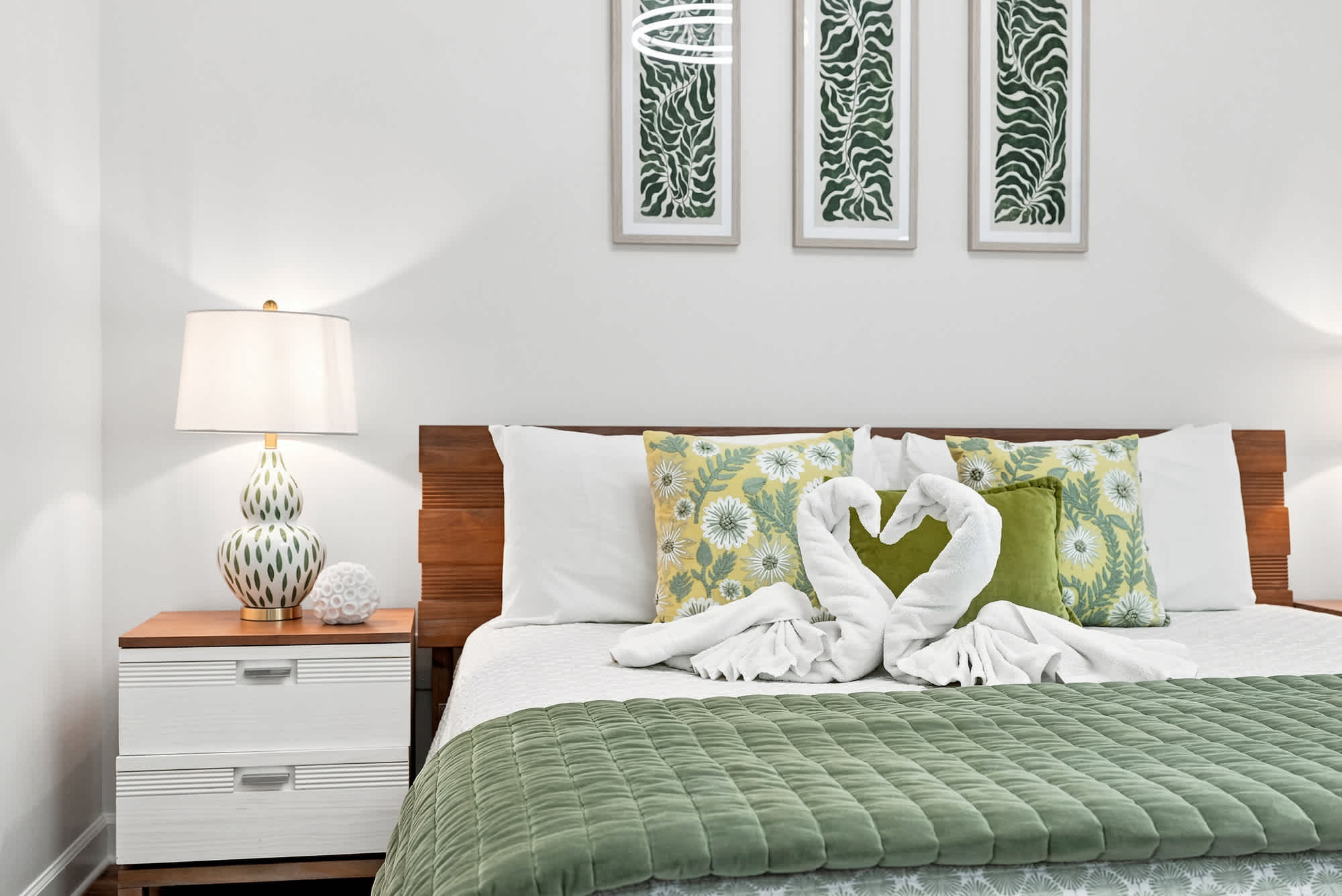 Splash 804E – Cozy bedroom with a bed adorned with decorative pillows and a towel sculpture shaped like a heart.