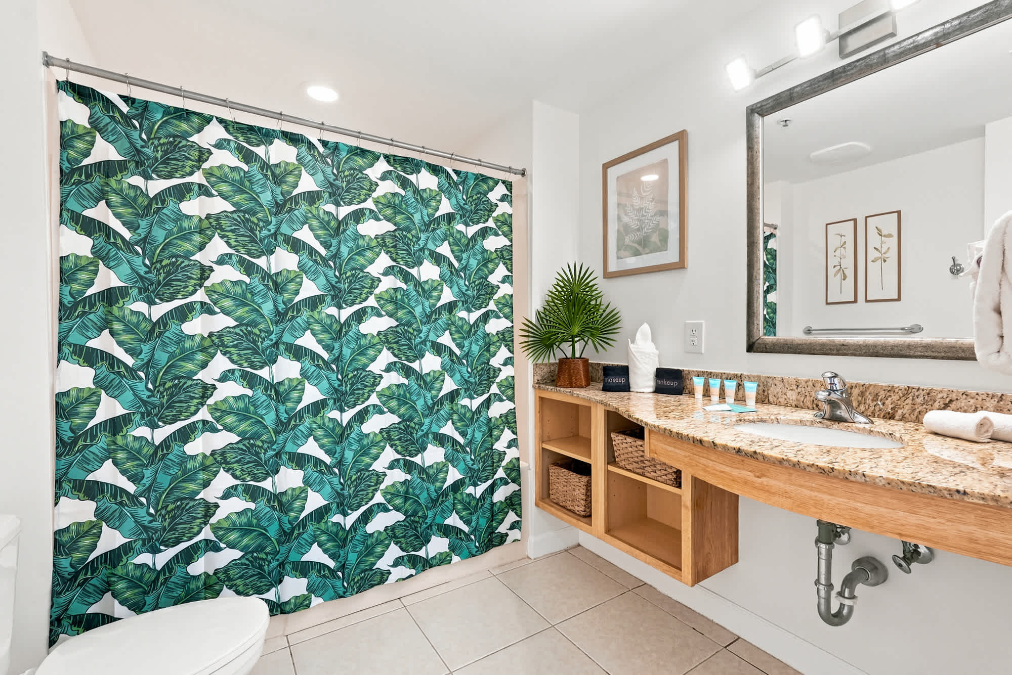 Splash 804E – Bathroom with a tropical shower curtain, granite vanity, and decorative plants.
