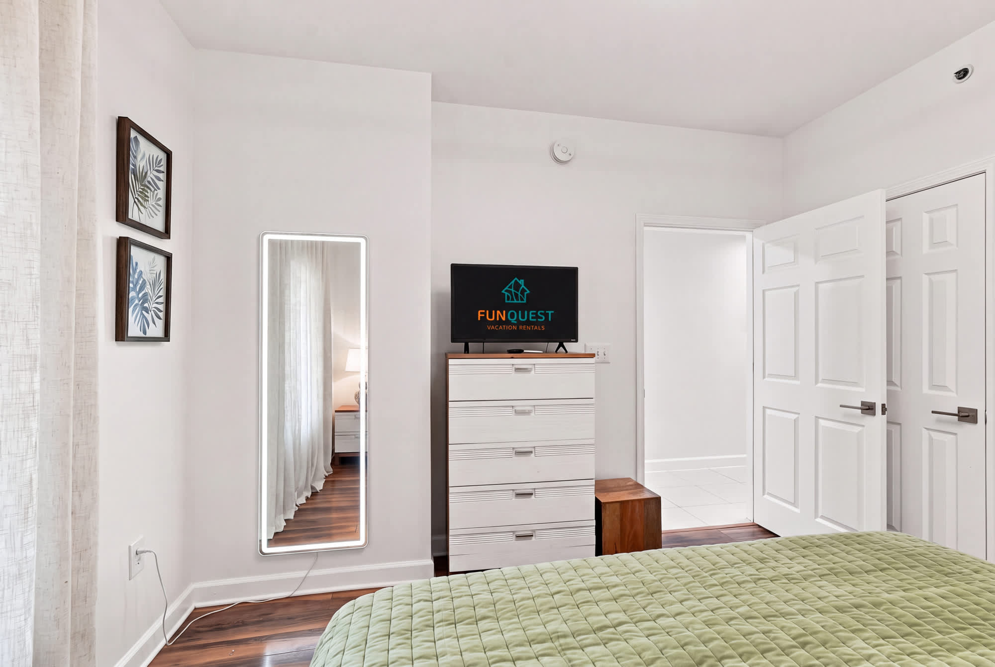 Splash 804E – Bedroom with green quilt, TV, mirror, and two doors leading to other areas.