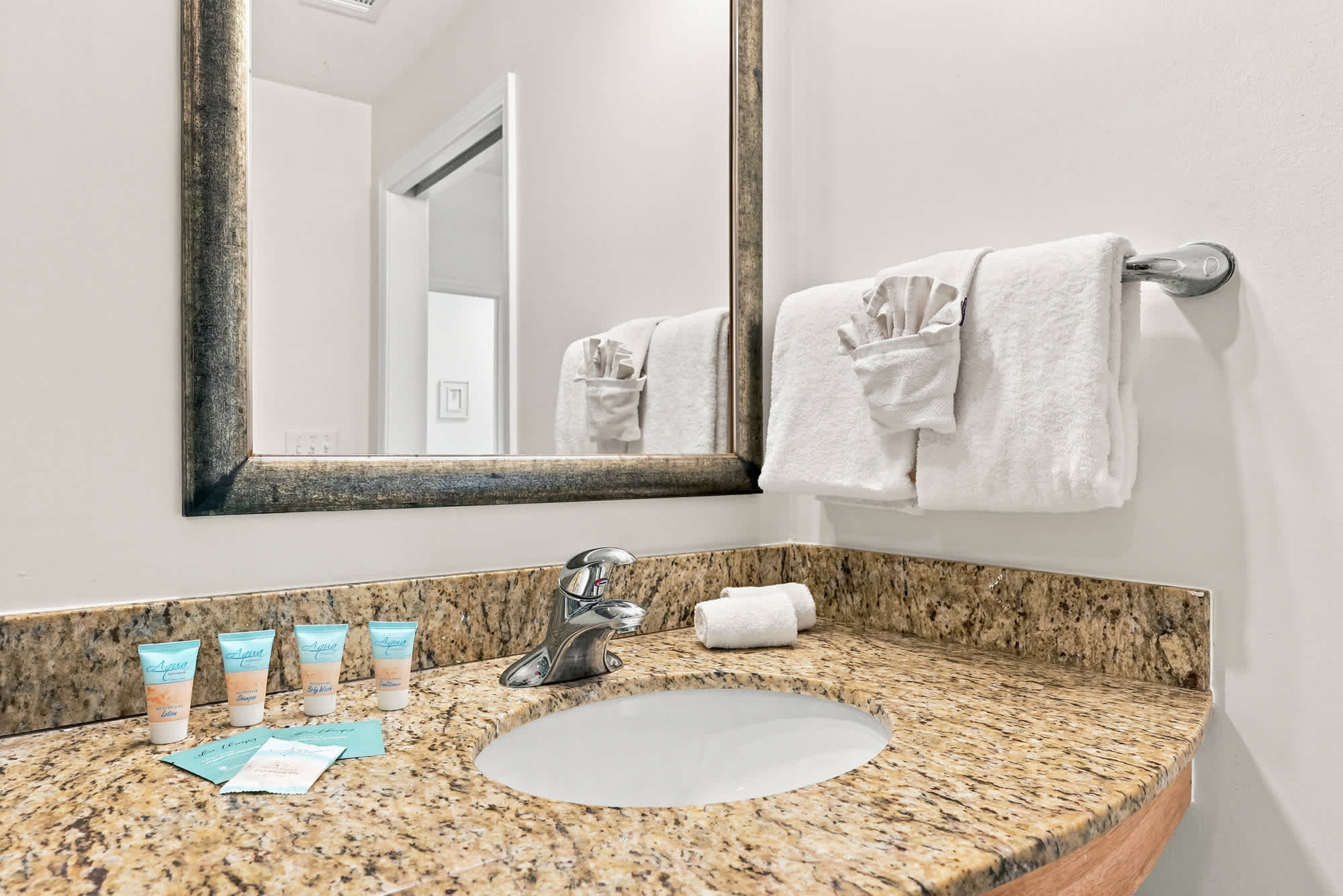 Splash 804E – Bathroom sink with granite countertop, mirror, toiletries, and towels displayed.