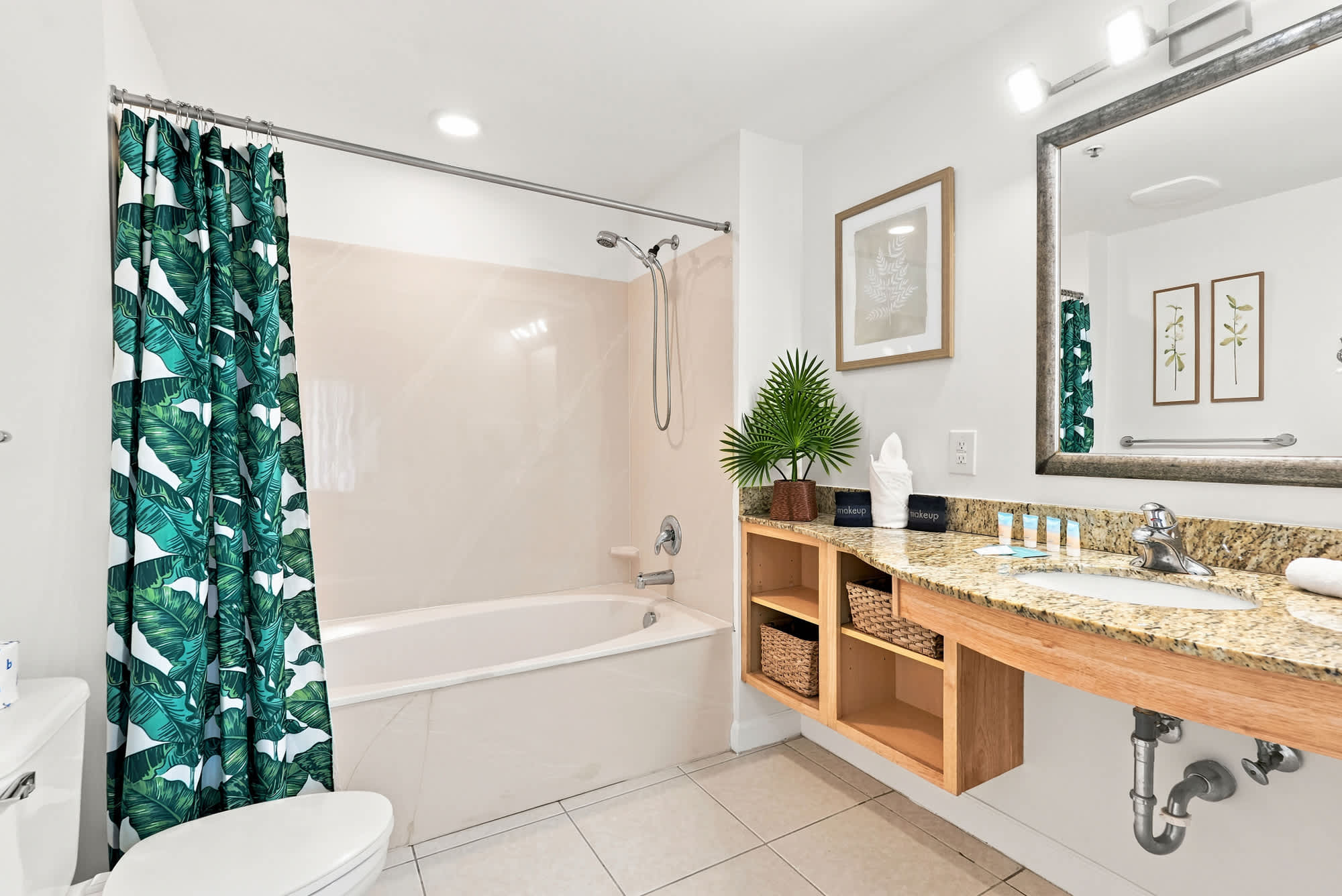 Splash 804E – Bright bathroom with tub, green leaf shower curtain, and granite counter with sink and storage.