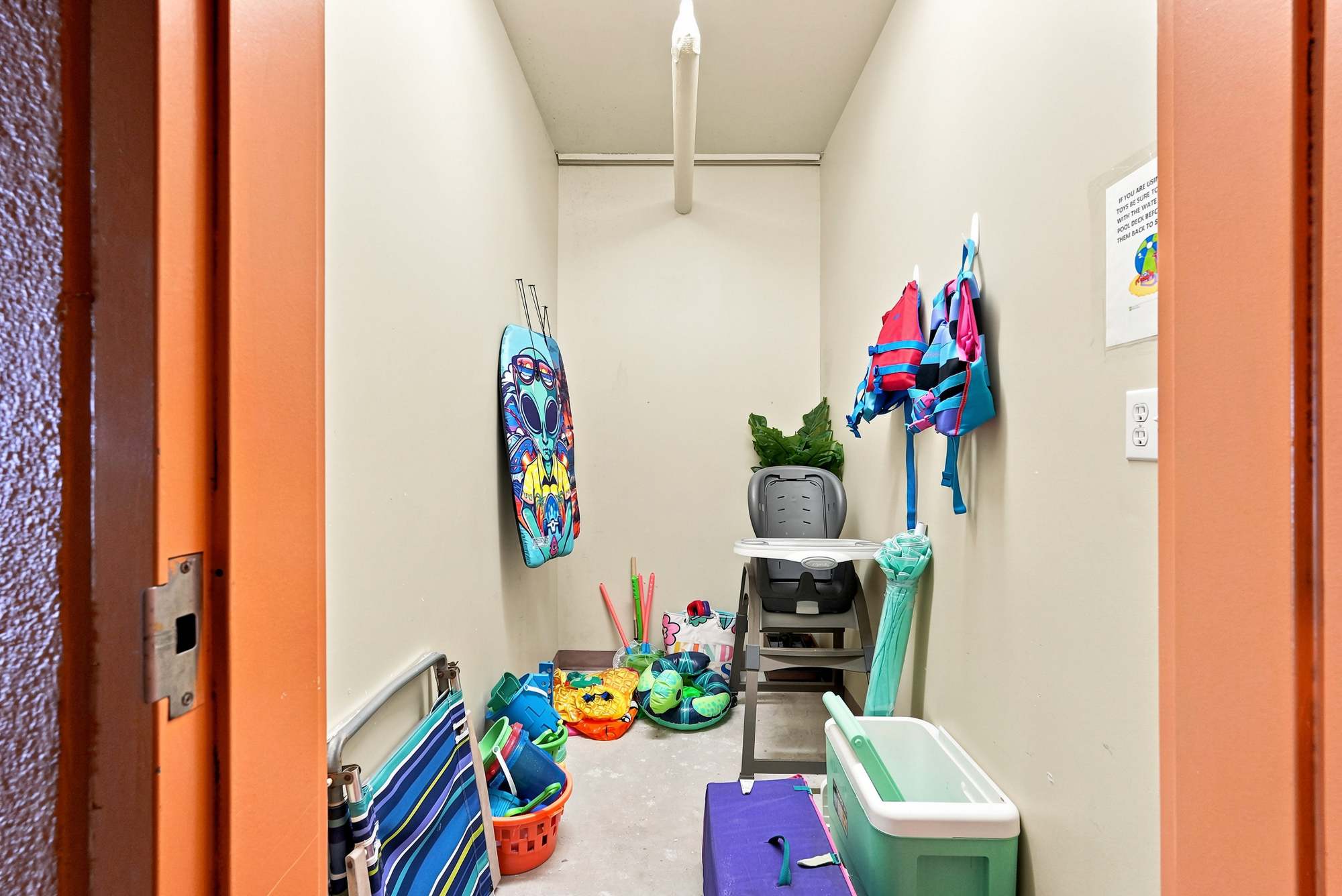 Splash 804E – Storage room with beach toys, floats, a high chair, and life jackets hanging on the wall.