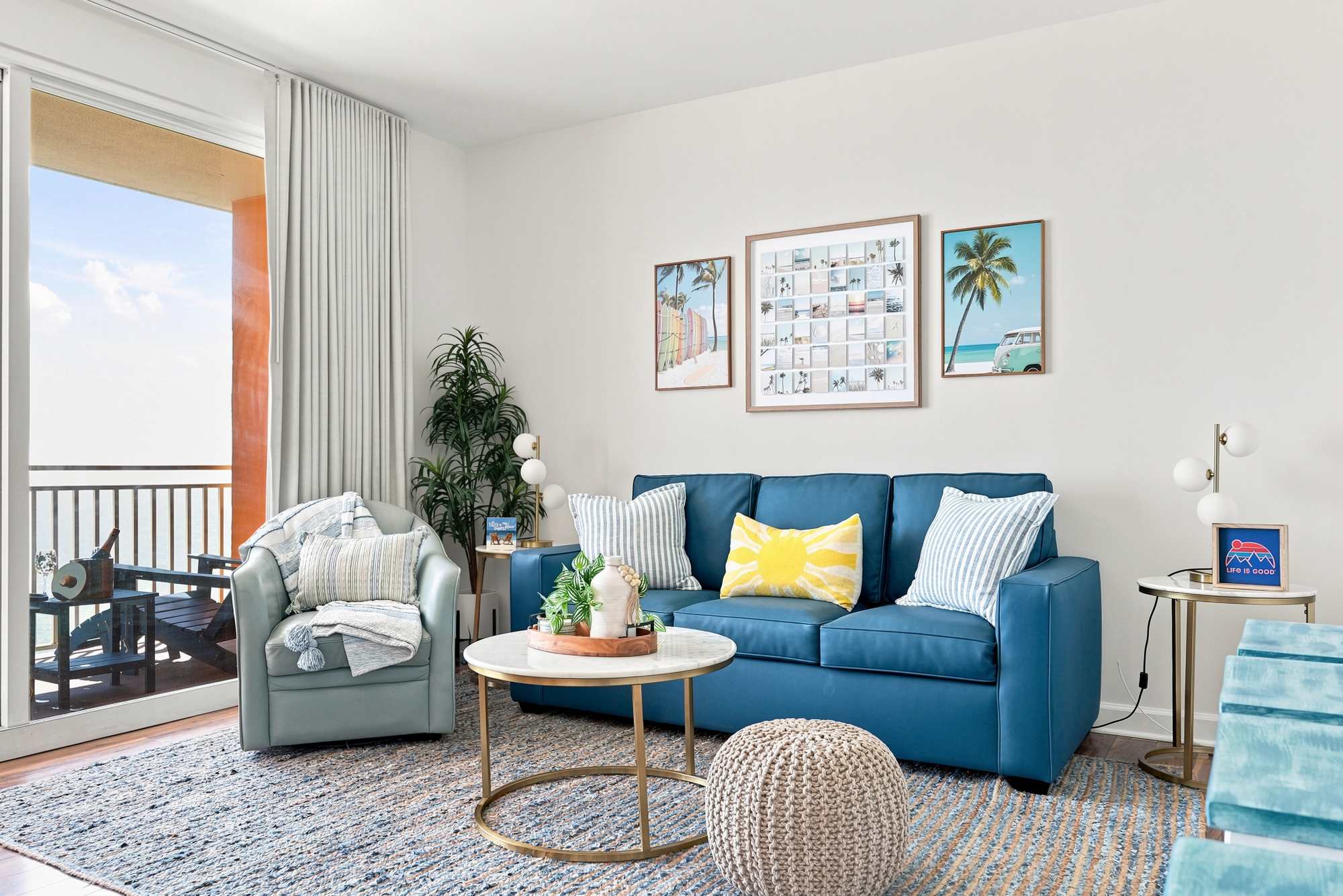 Splash 804E – Bright living room with a blue sofa, cozy chairs, coffee table, and balcony view.