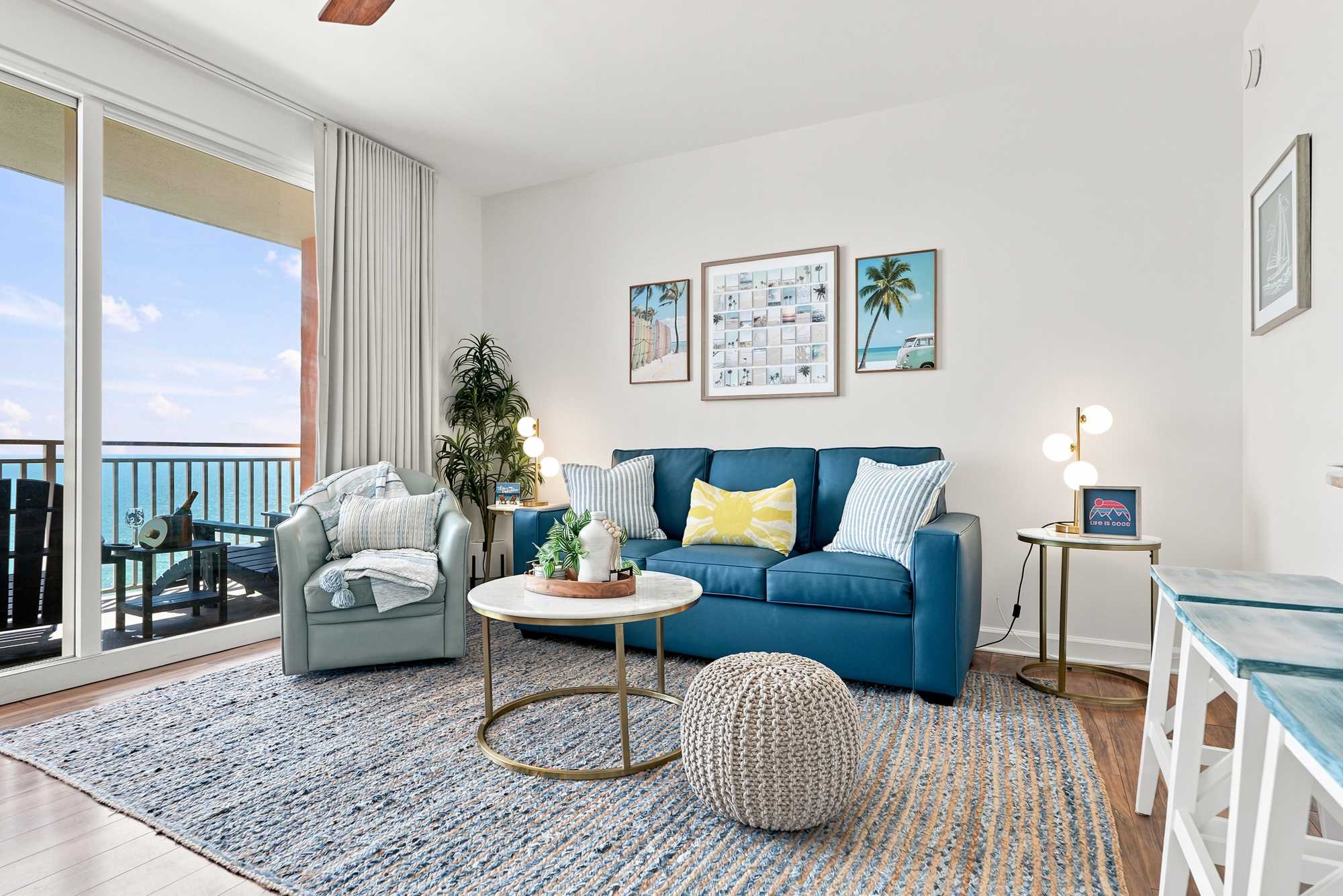 Splash 804E – Living room with ocean view, teal sofa, light rug, round coffee table, and accent chairs.