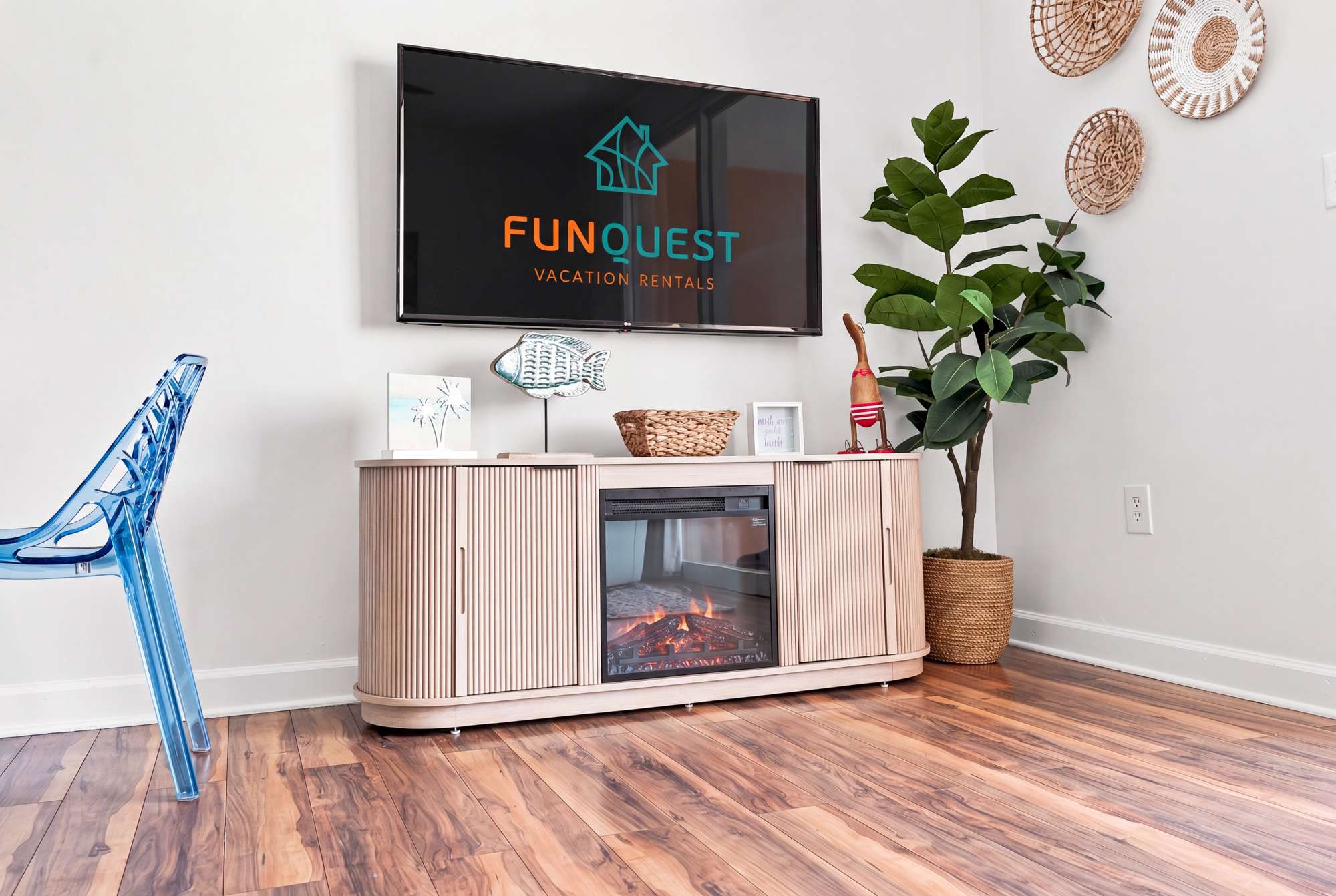 Splash 804E – Living room with a TV, blue chair, decorative plant, and a media console with an electric fireplace.