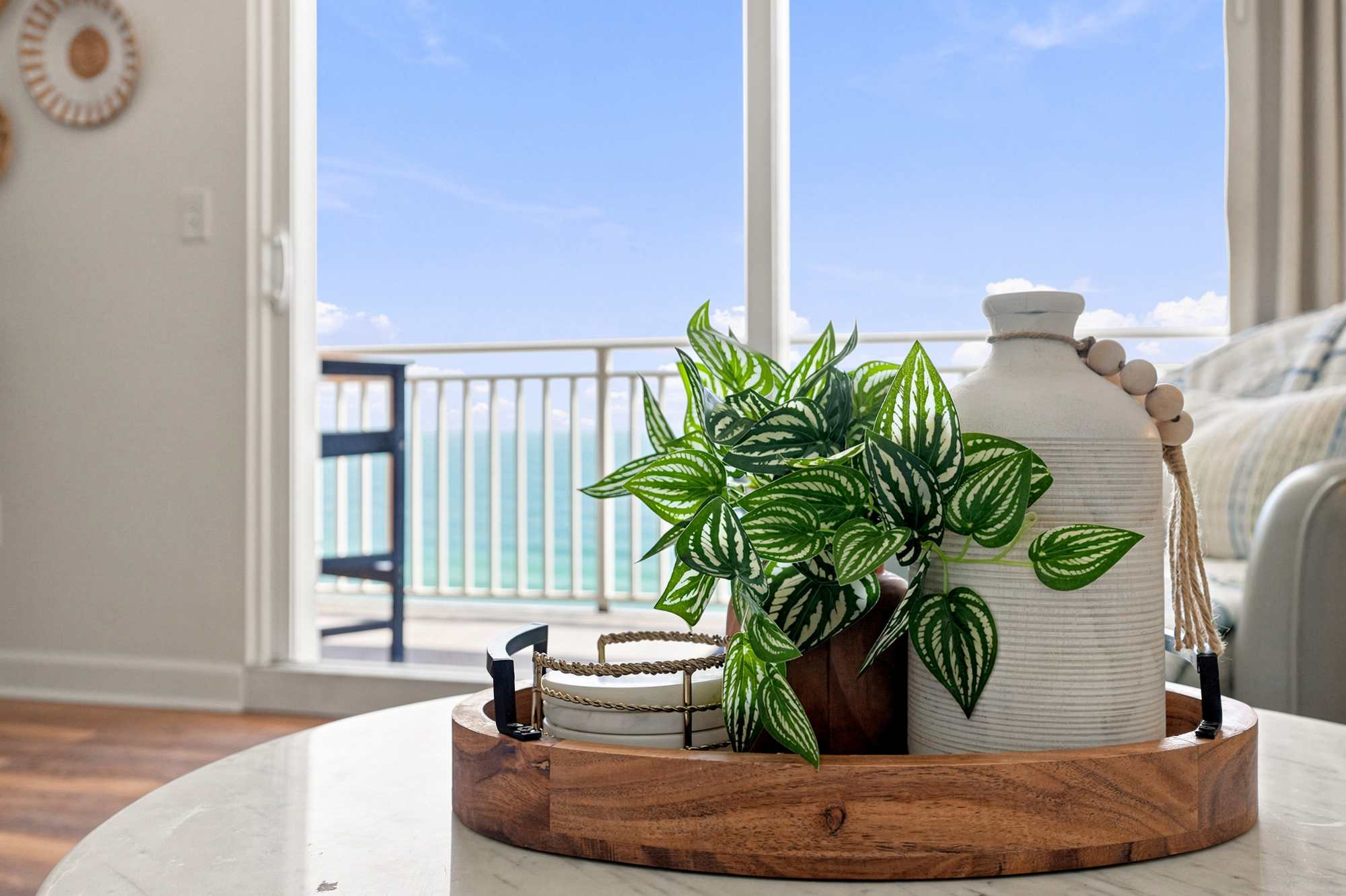 Splash 804E – Living room with a table tray, potted plant, and ocean view through large glass doors.
