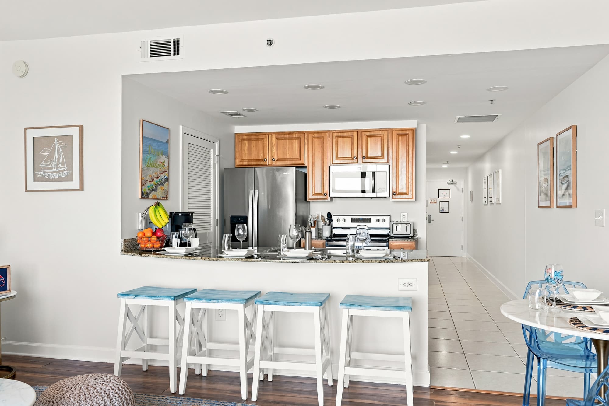 Splash 804E – Open kitchen with stainless steel appliances, bar stools, and dining area. Decor includes framed artwork.
