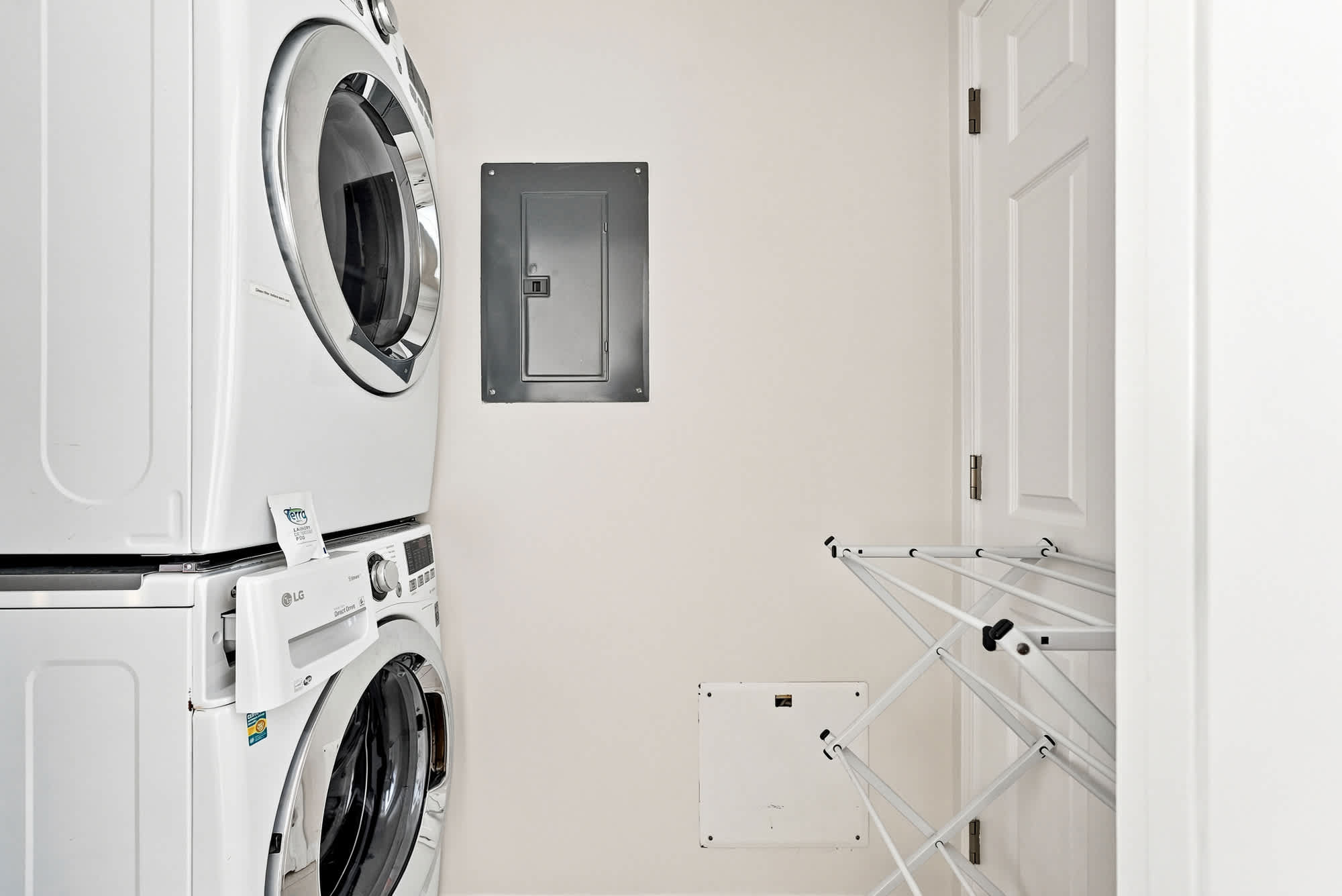 Splash 804E – Laundry room with stacked washer and dryer, electrical panel, and a collapsible drying rack.