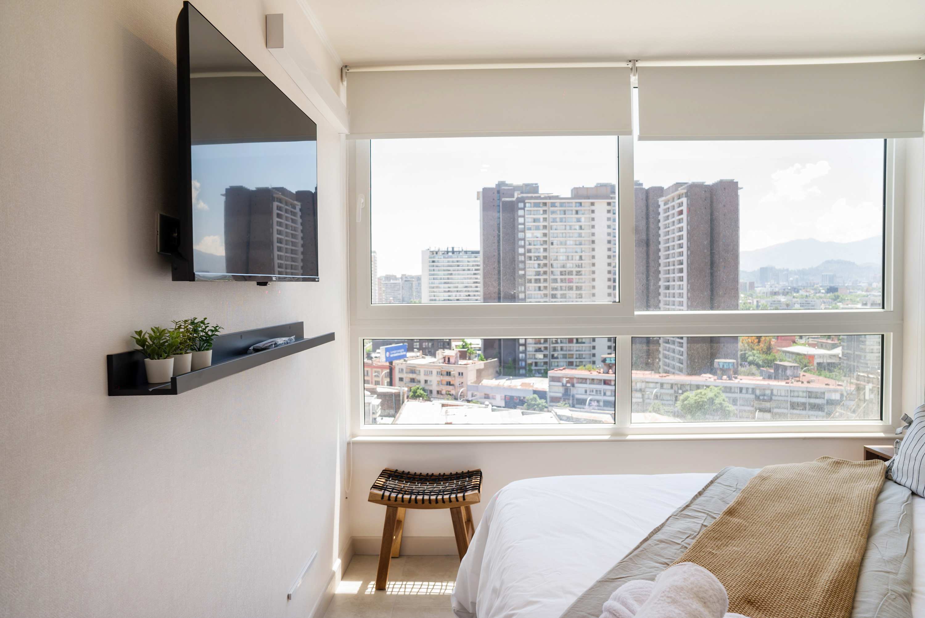 Enjoy stunning city views from this modern bedroom with a wall-mounted TV and stylish decor.