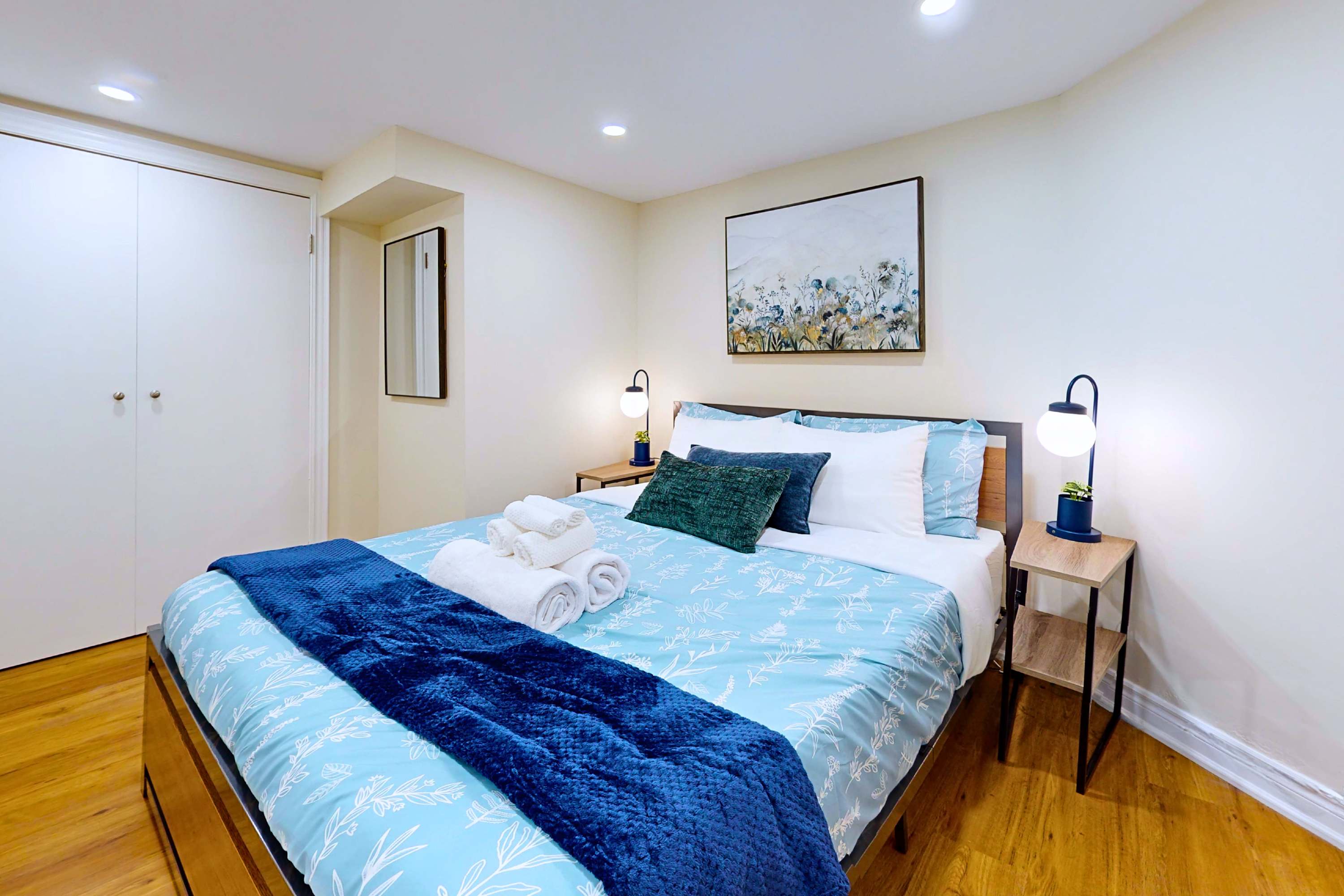 Relaxing bedroom space with a queen bed, lamps, and cabinet storage.