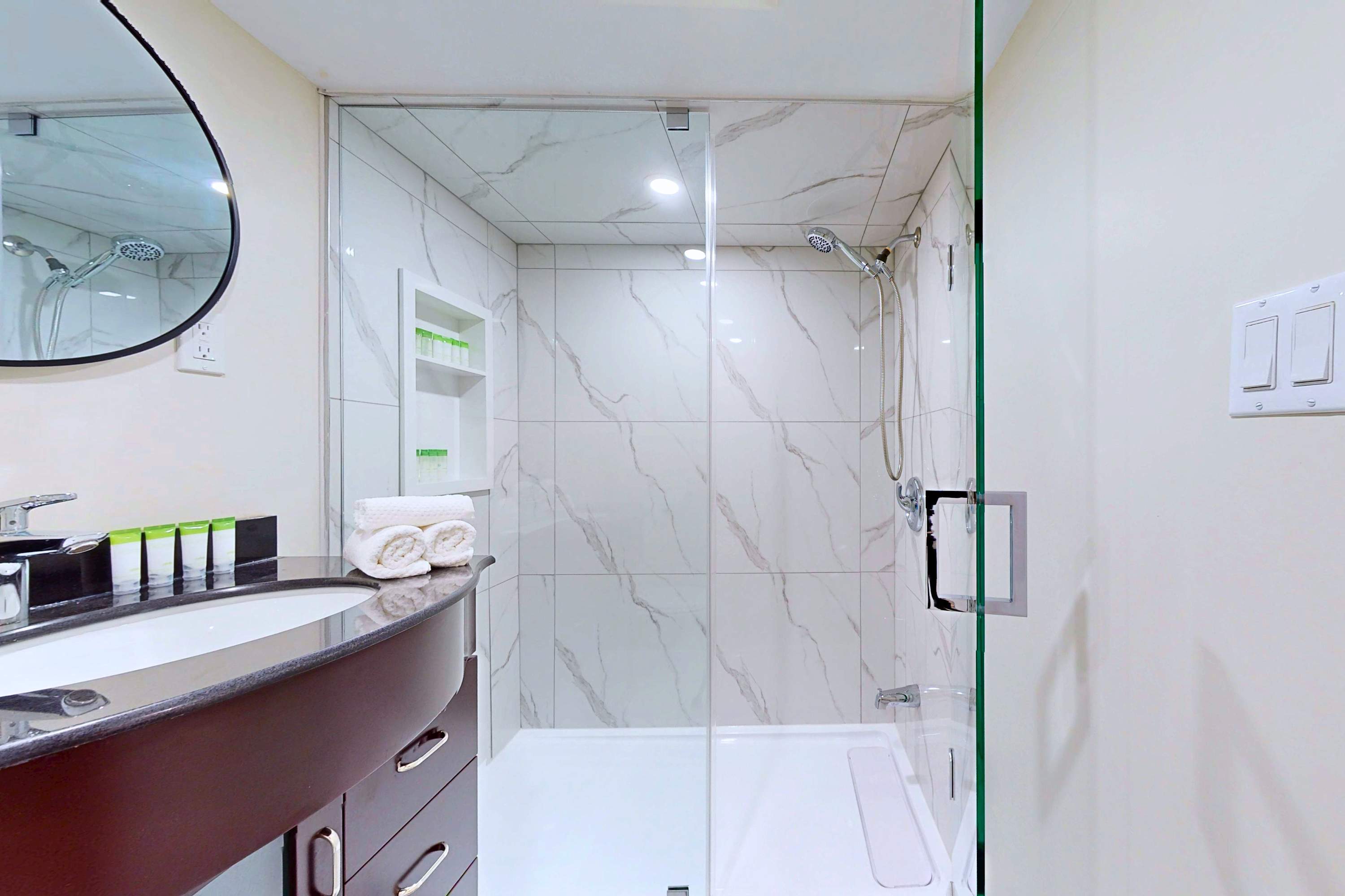 Complete bathroom space with a walk-in shower, sink, and mirror.