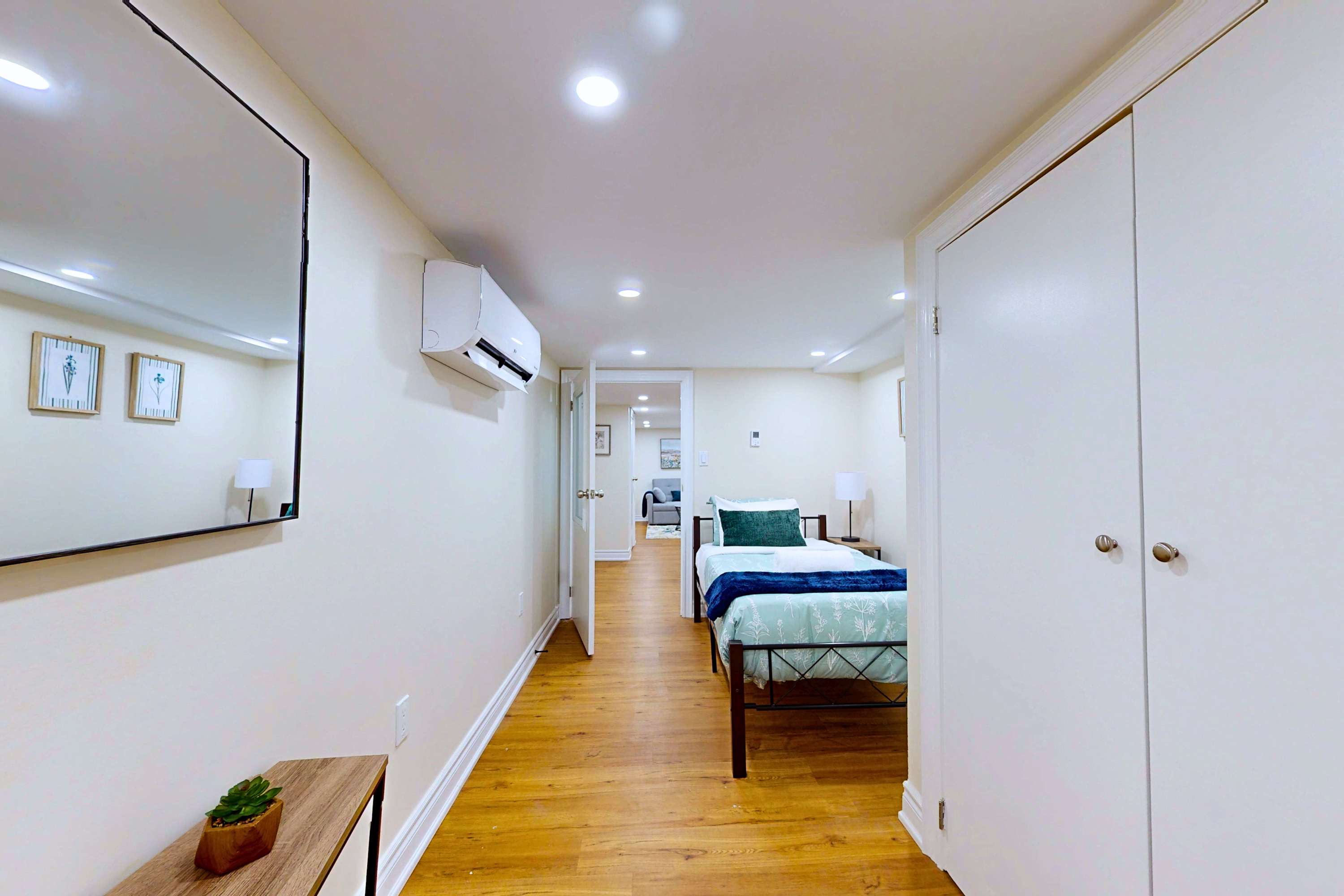 Air-conditioned room with a single bed, mirror, and cabinet.