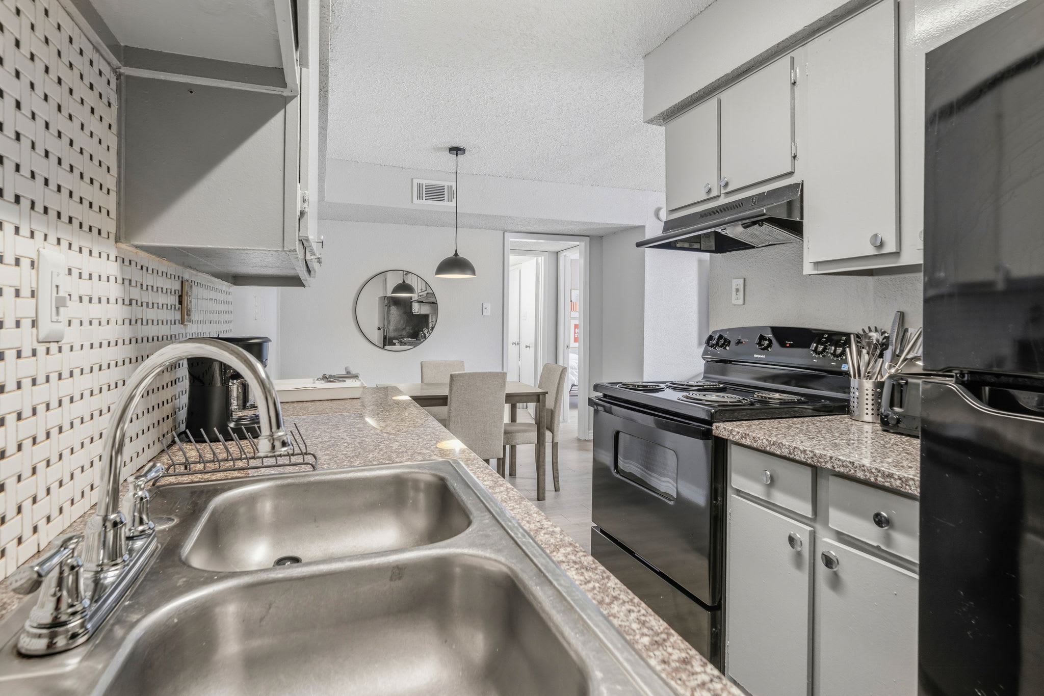Private kitchen with a geometric tile backsplash, granite-look counters, full-size electric range, and a four-seat dining table for shared meals.