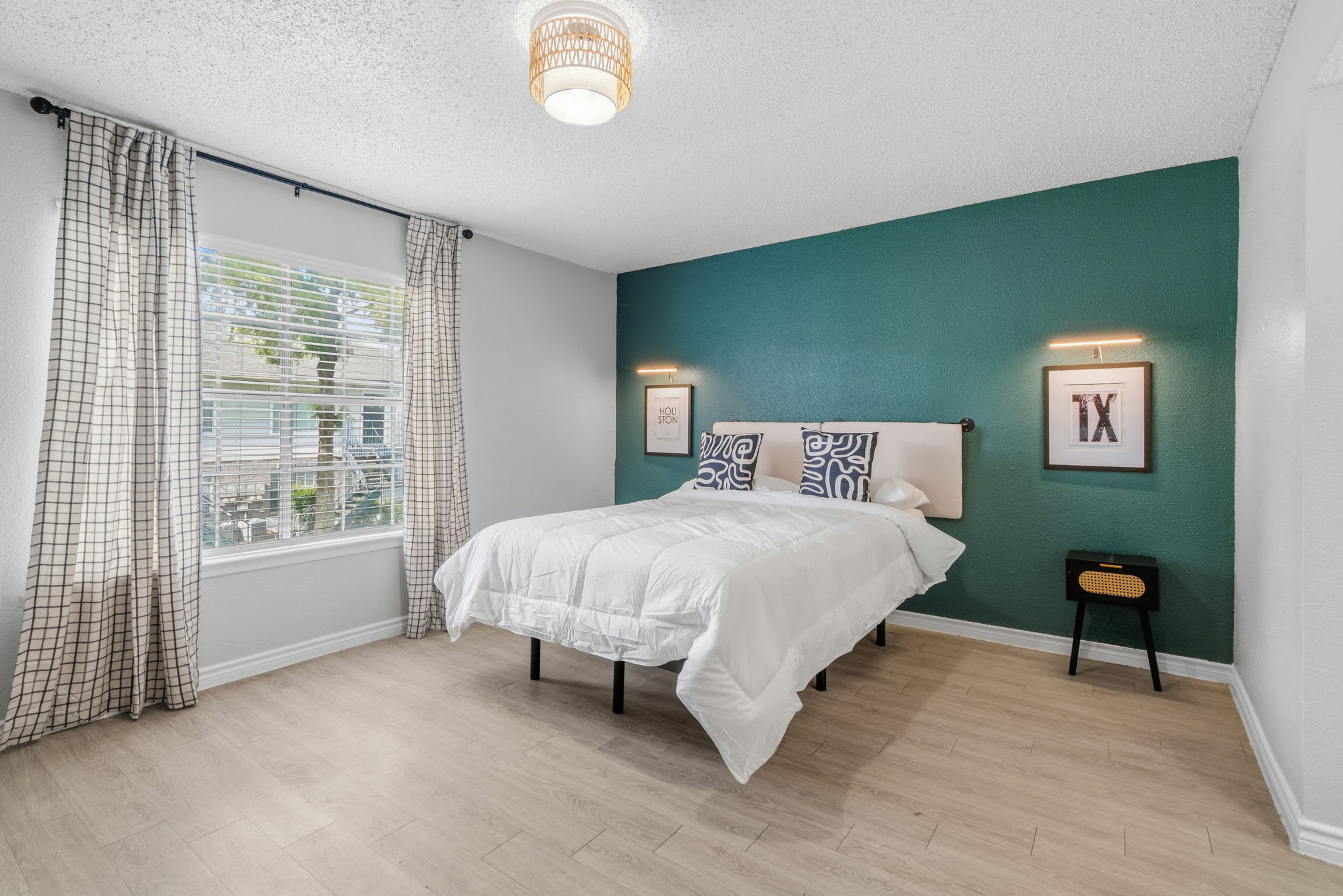 Cozy bedroom with stylish decor and ample natural light, perfect for a relaxing stay.