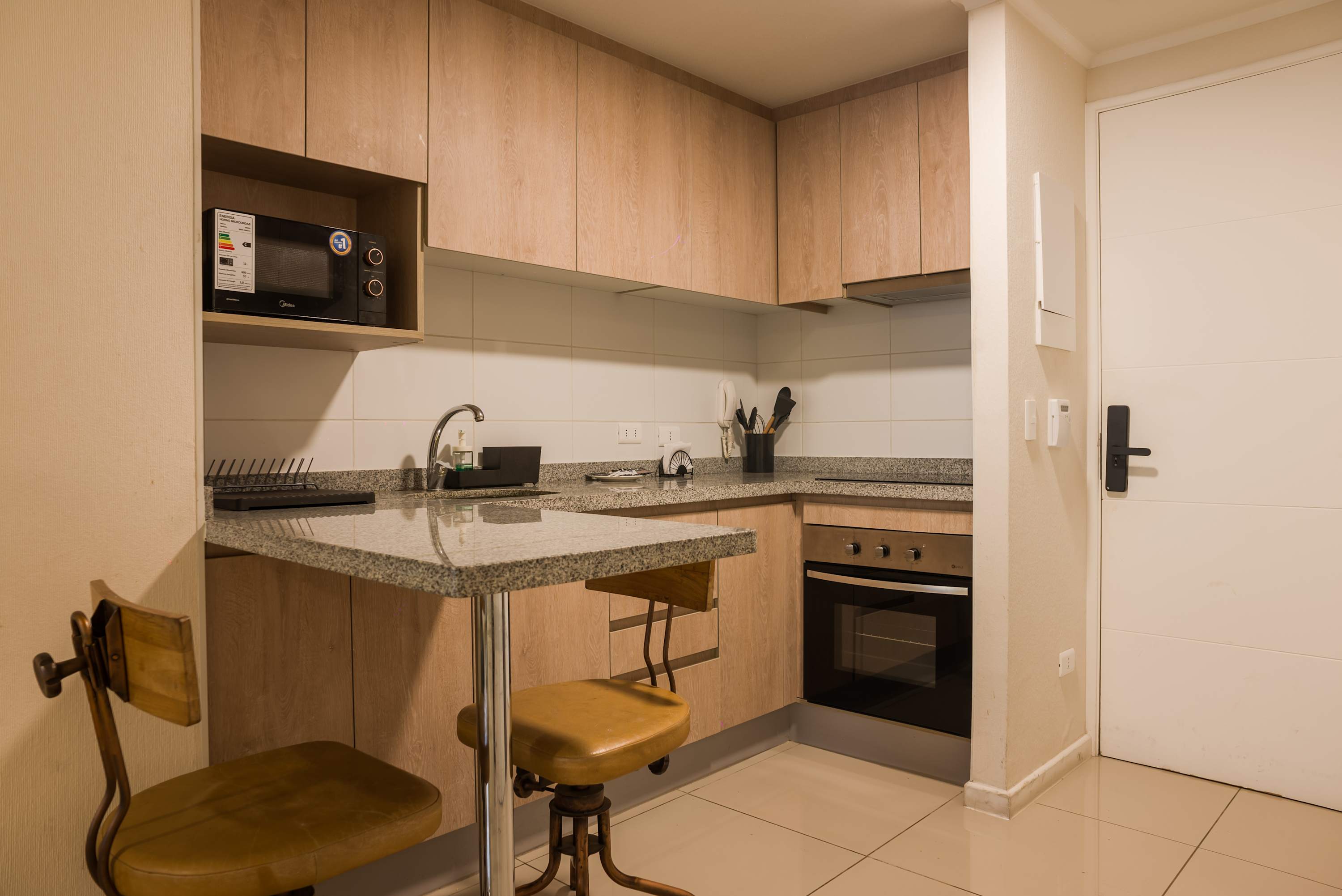 Modern kitchen with sleek granite countertops and cozy seating, perfect for a quick meal or morning coffee.