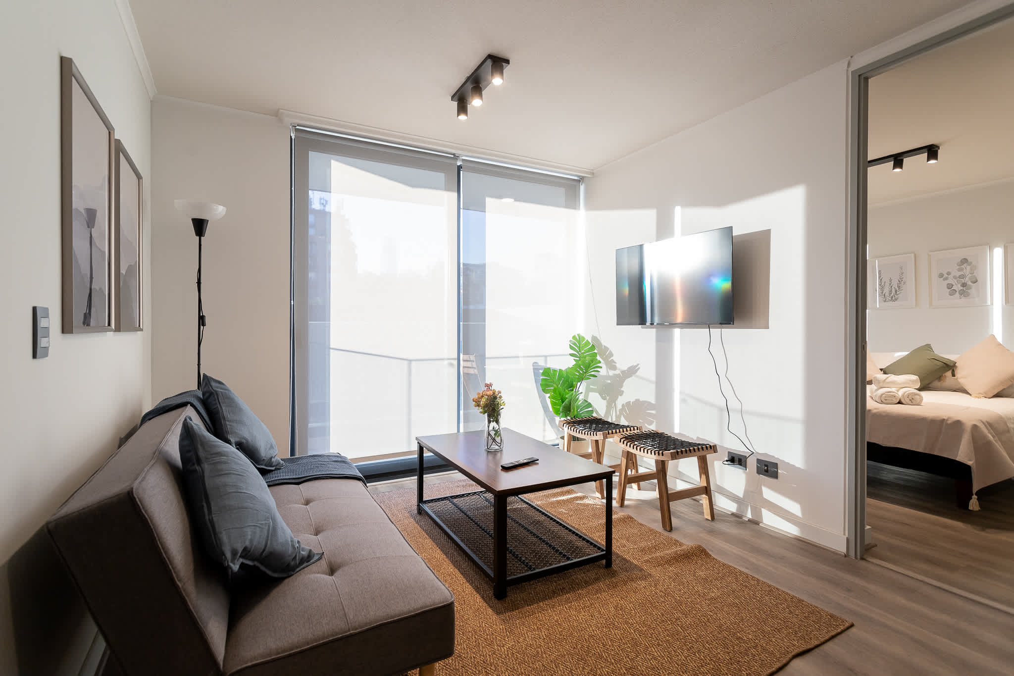 Bright and modern living area with a cozy sofa and wall-mounted TV, perfect for relaxation.