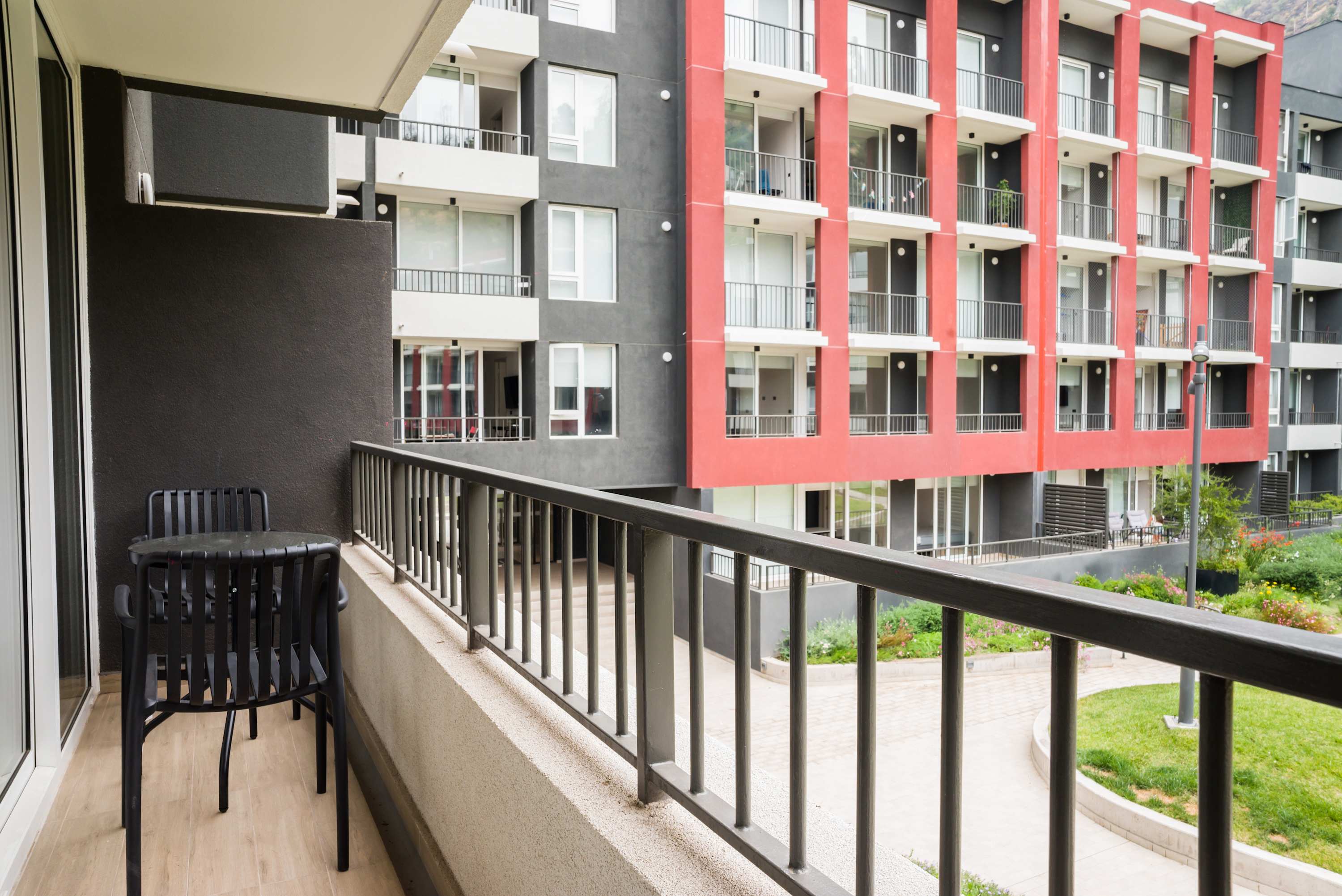 Enjoy your morning coffee on this cozy balcony with views of the vibrant apartment complex.