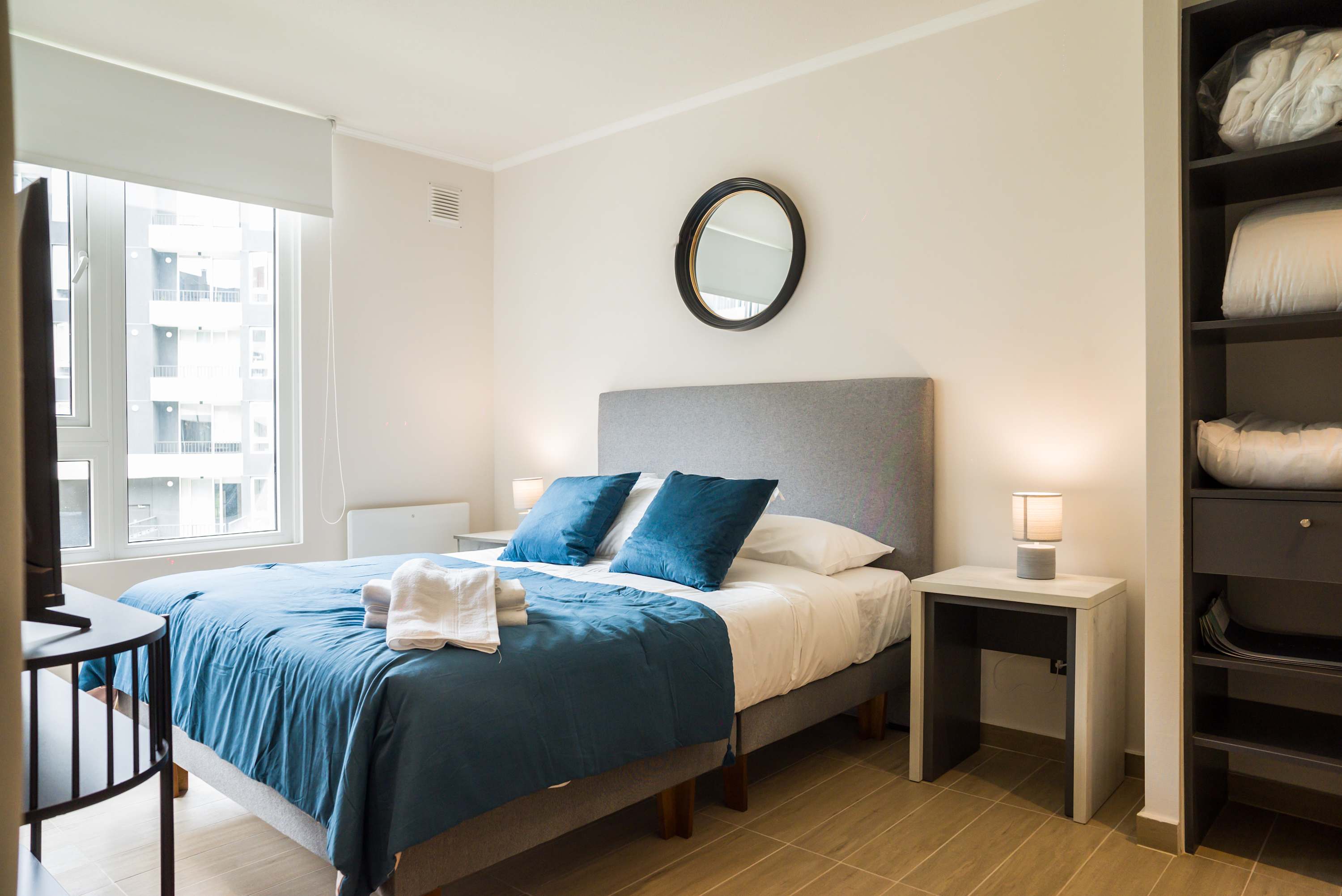 Cozy bedroom with natural light and modern decor, perfect for a relaxing stay.