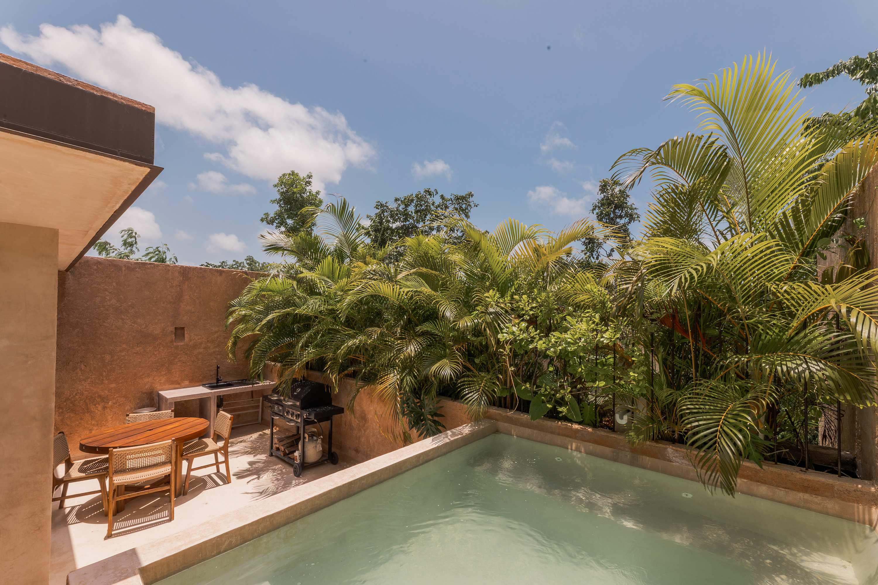 Outdoor plunge pool with BBQ and dining tables.