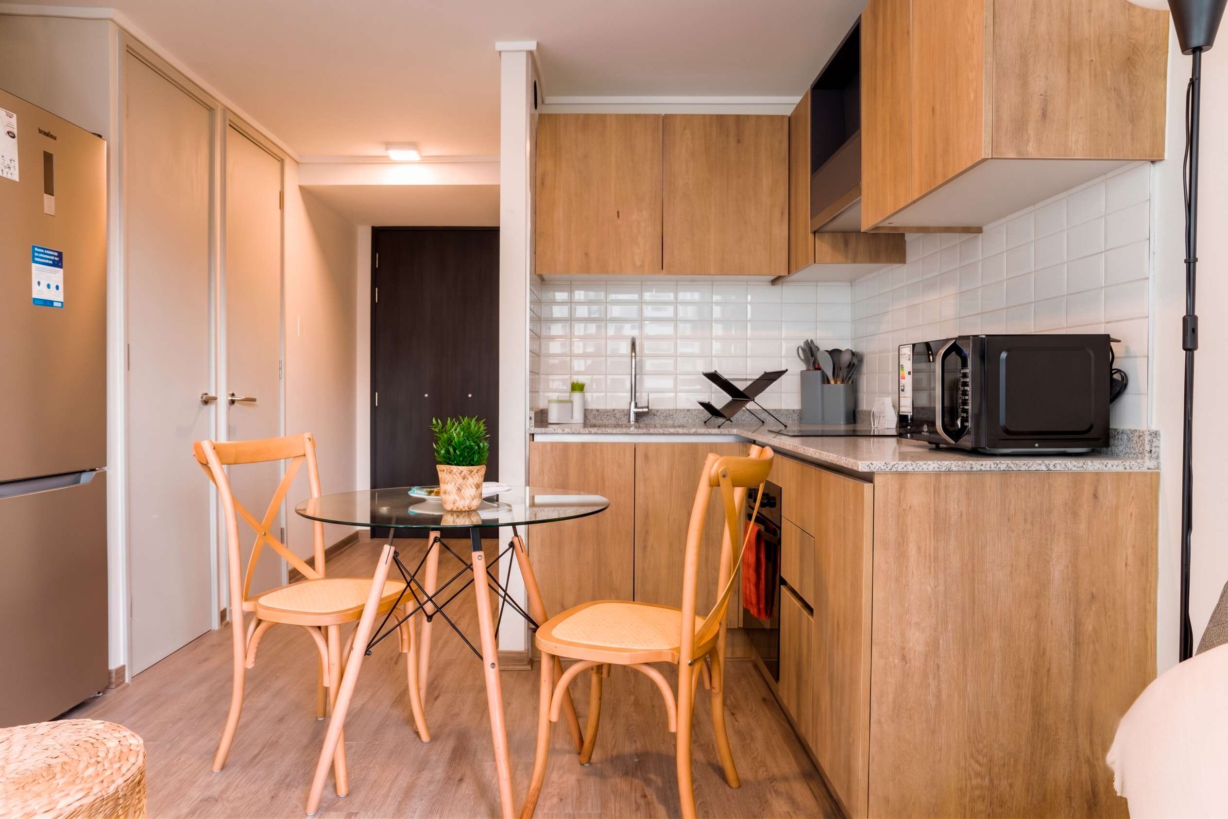 Cozy and modern kitchen with sleek wooden finishes and a charming dining area, perfect for intimate meals.