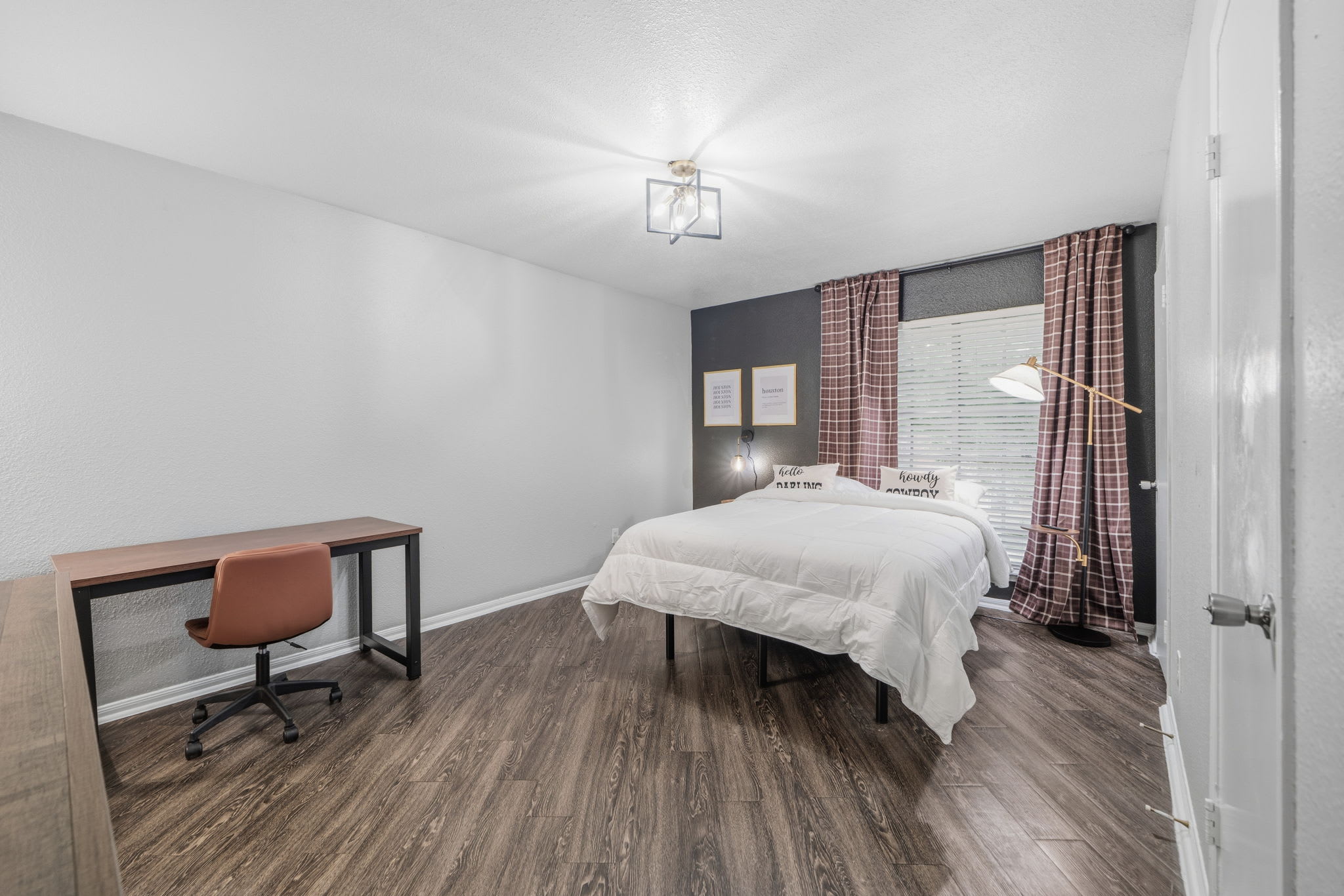 Cozy bedroom with workspace and stylish decor, perfect for relaxation and productivity.
